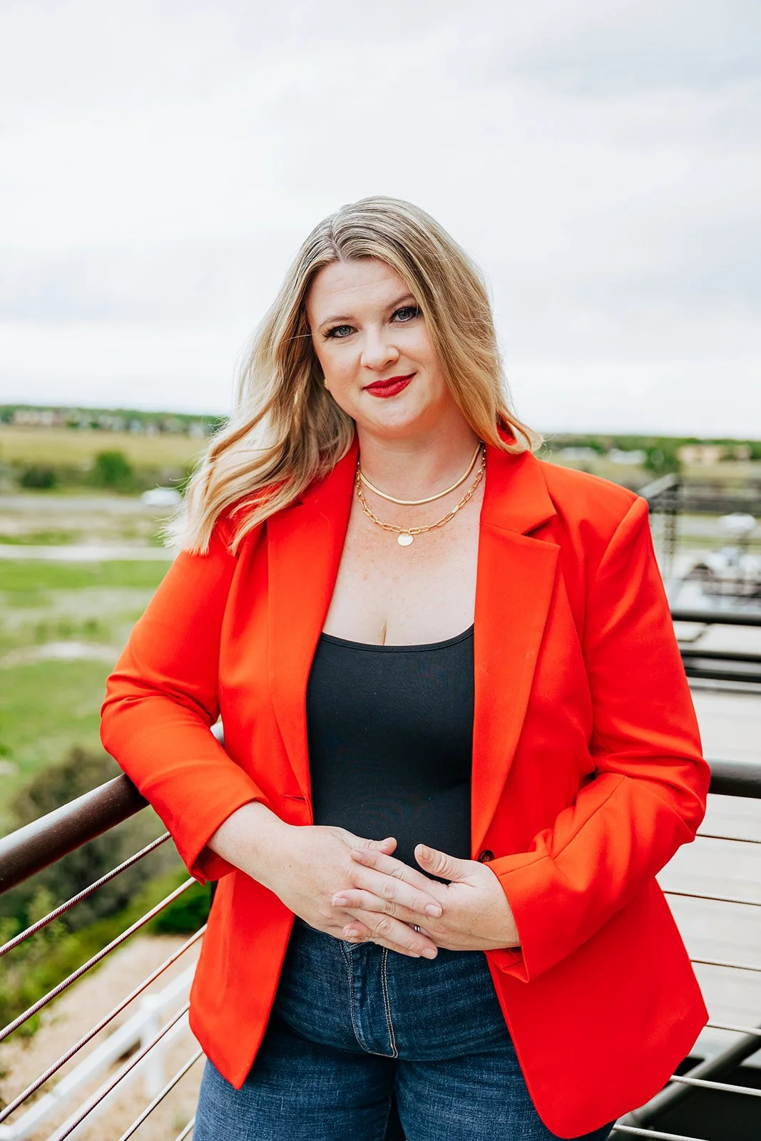 Ashley Heckathorn realtor brand photo, wearing a red blazer and smiling.
