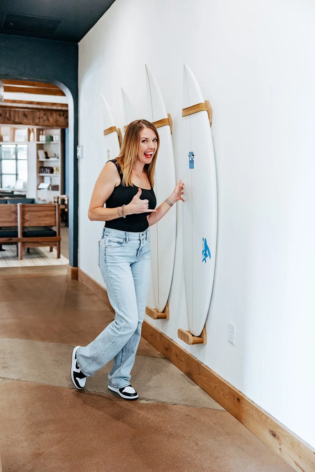 Nicolette Thomas realtor posing next to a wake board, giving a thumbs up