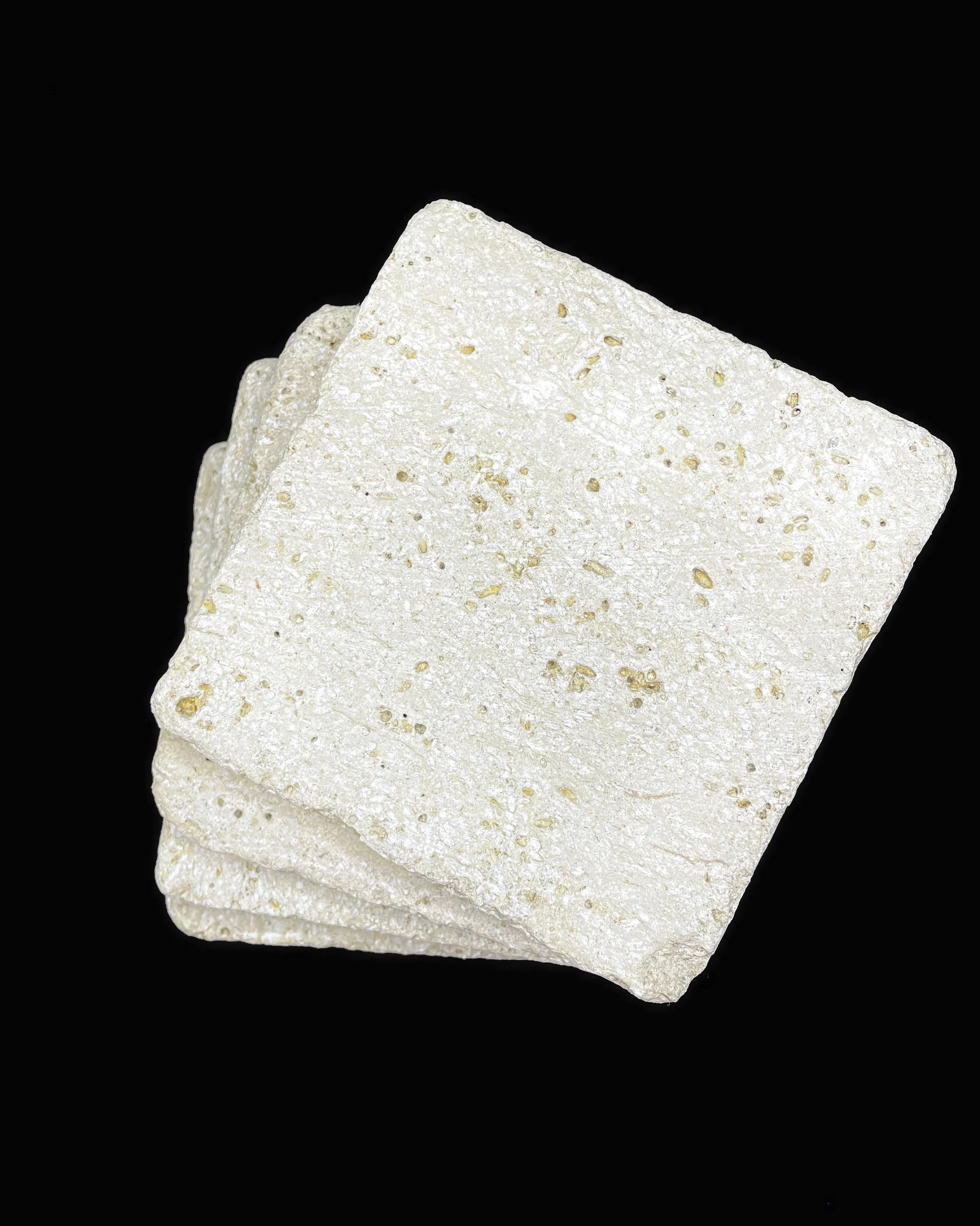 Four stacked white rice crackers against a black background.