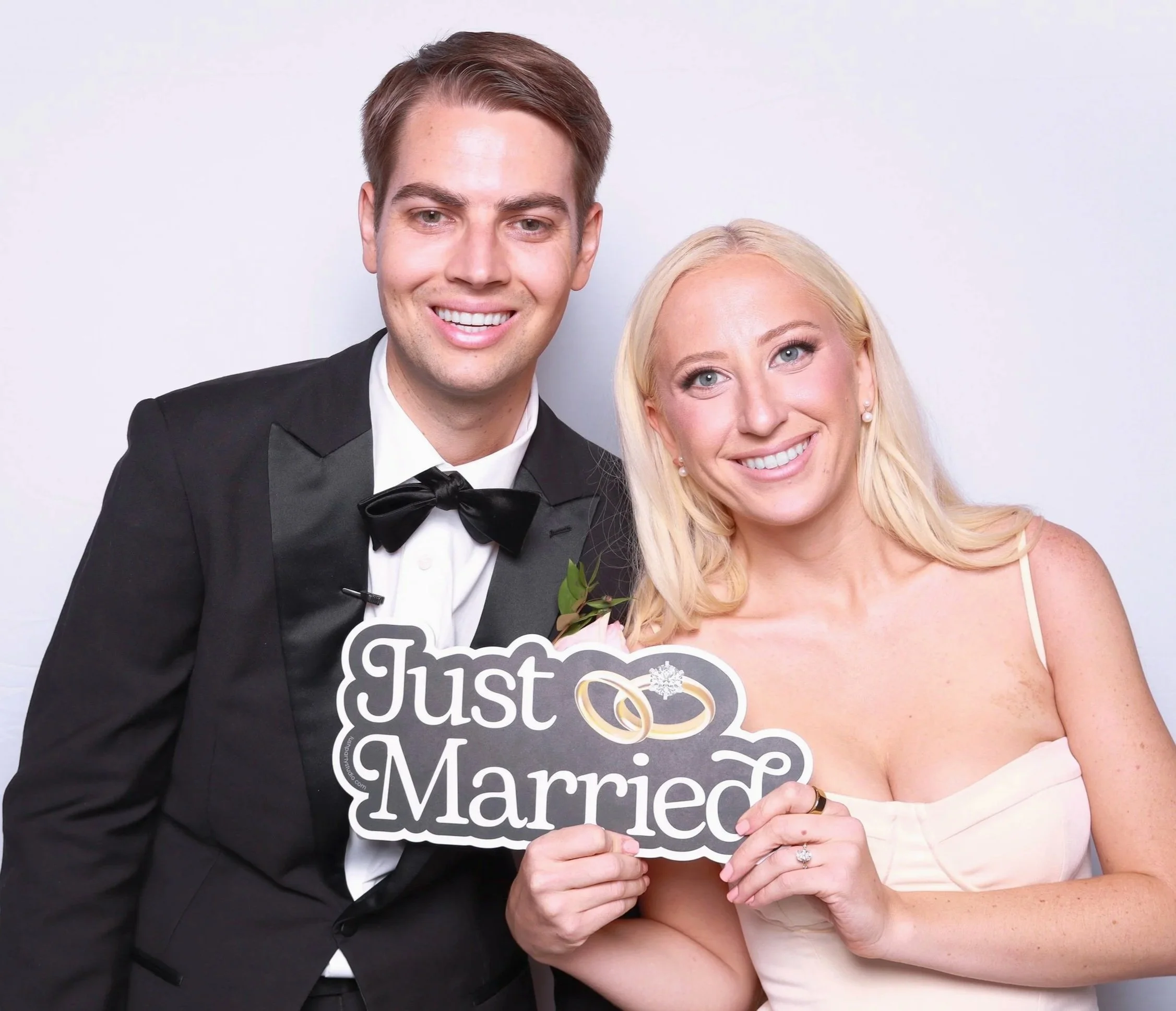 couple holding a just married prop with the photo booth at their wedding reception