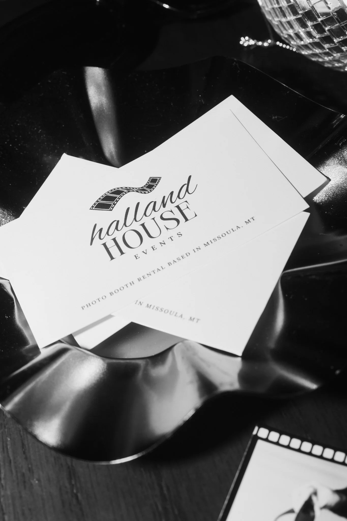 A business card for Halland House Events, a photo booth rental company based in Missoula, Montana, resting on a metallic surface.