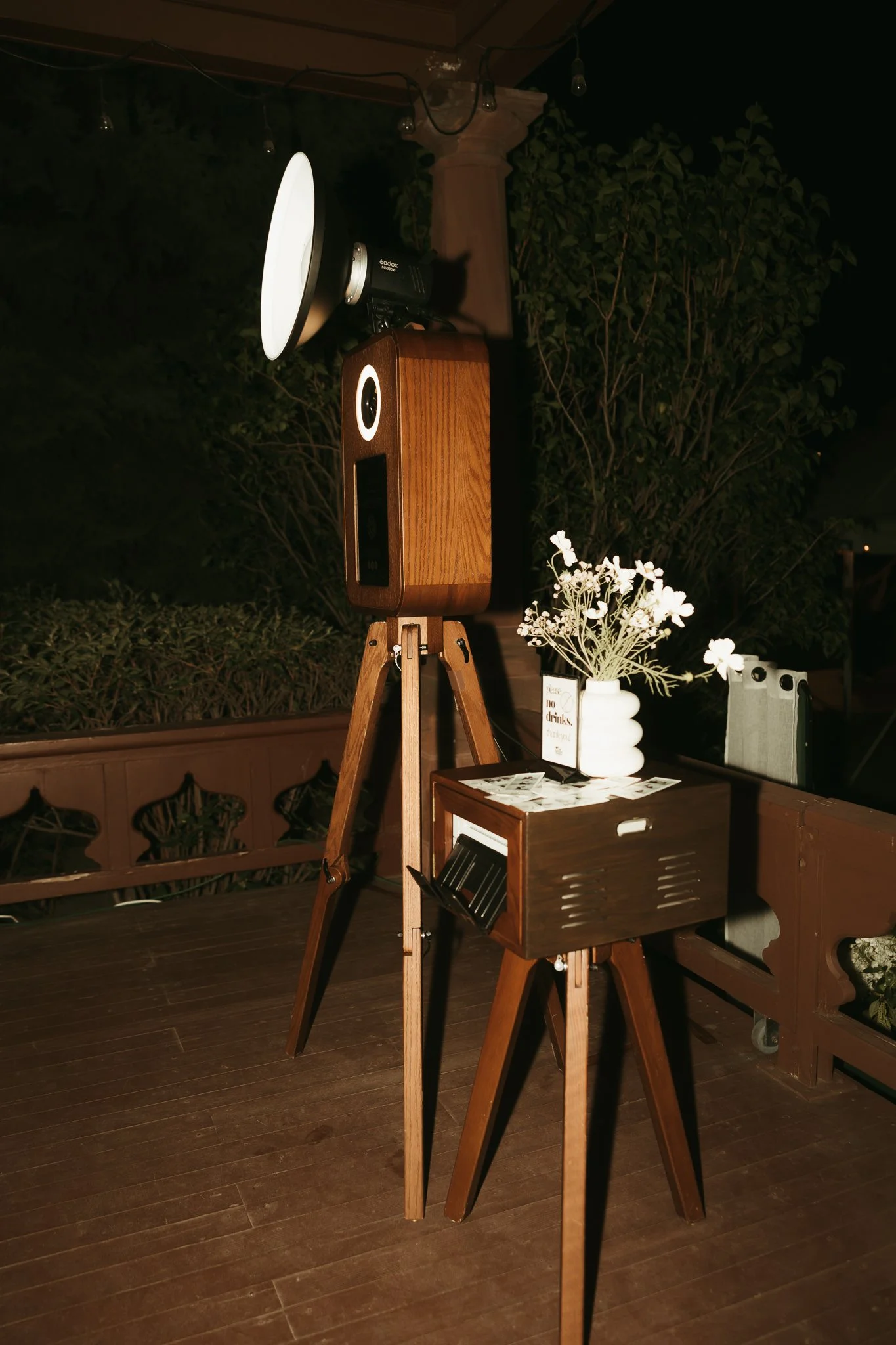 Missoula Montana Photo Booth Rental Set-up: dark brown wood shell with lighting equipment and a floral arrangement on top of the printer