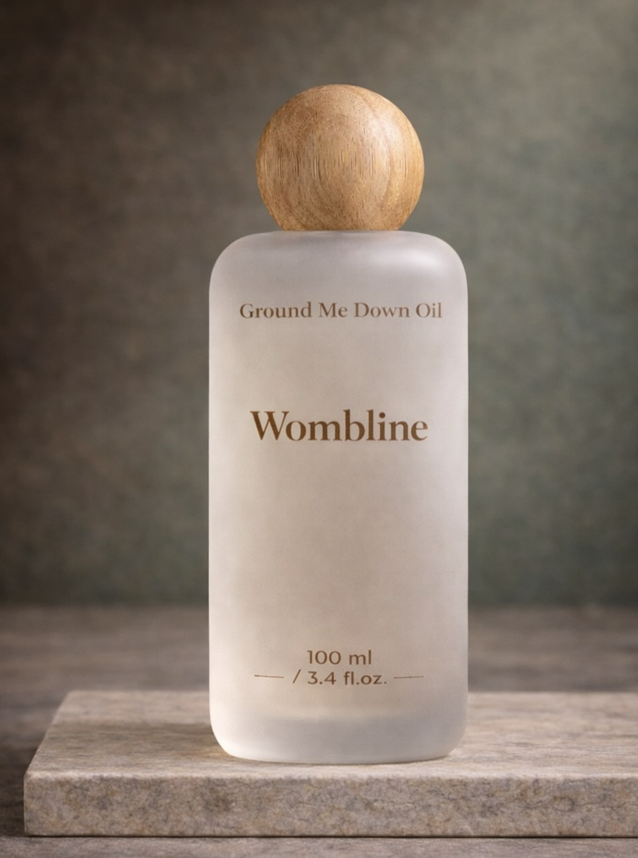 A frosted glass bottle with a wooden cap labeled 'Ground Me Down Oil' by Wombline, containing 100 milliliters or 3.4 fluid ounces.