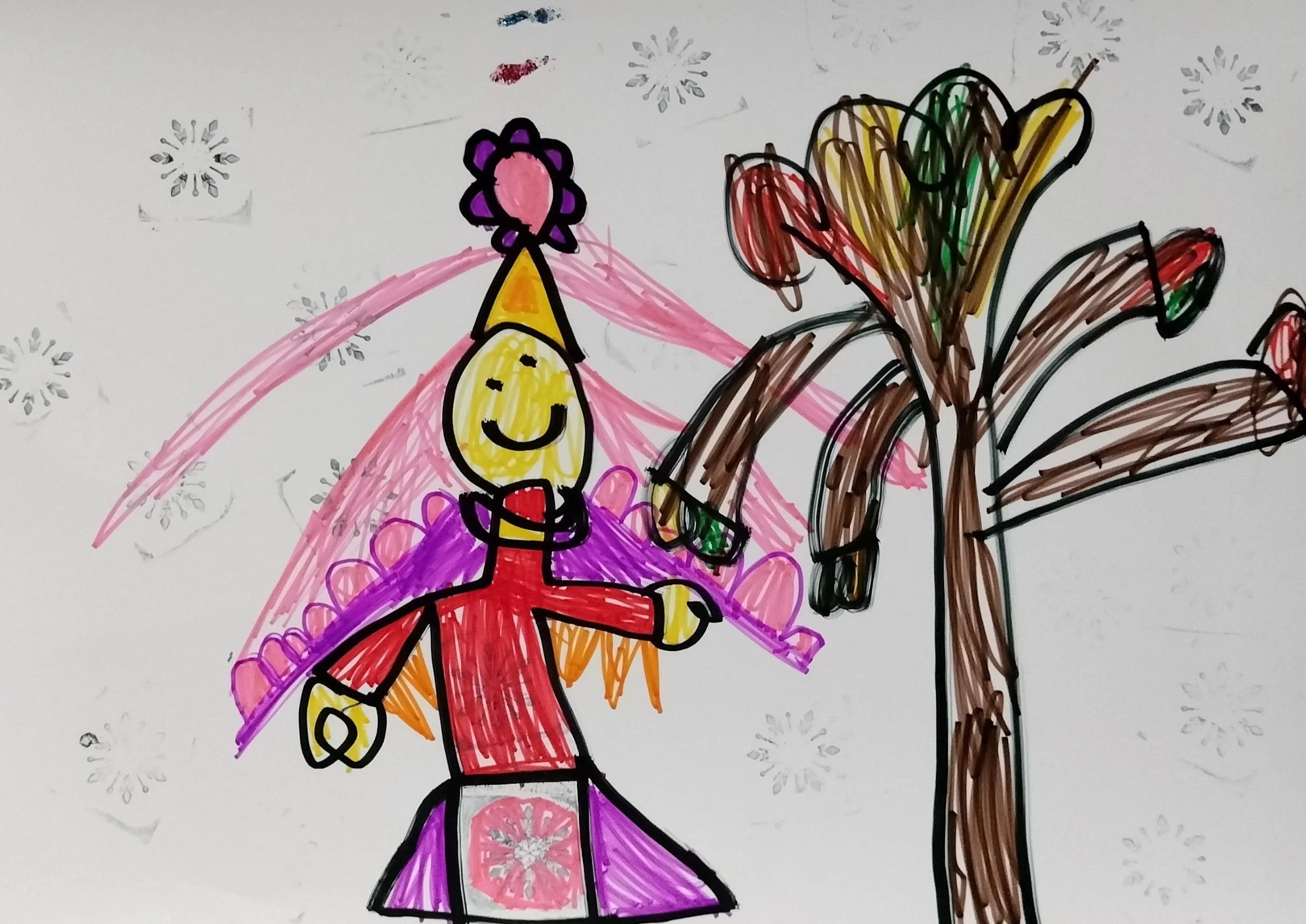 Child's colorful drawing of a smiling figure wearing a pink dress with a snowflake pattern, a yellow party hat with a purple flower, standing next to a tree with brown trunk and multicolored leaves, and light snowflakes on the background.