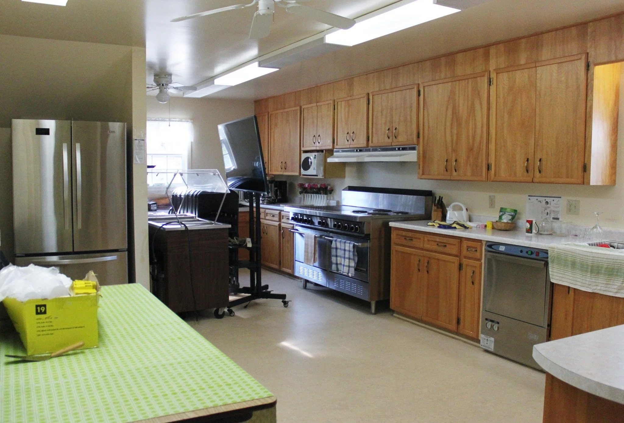 Kitchen with wood cabinets, stainless steel appliances, and a green checkered tablecloth on the table.