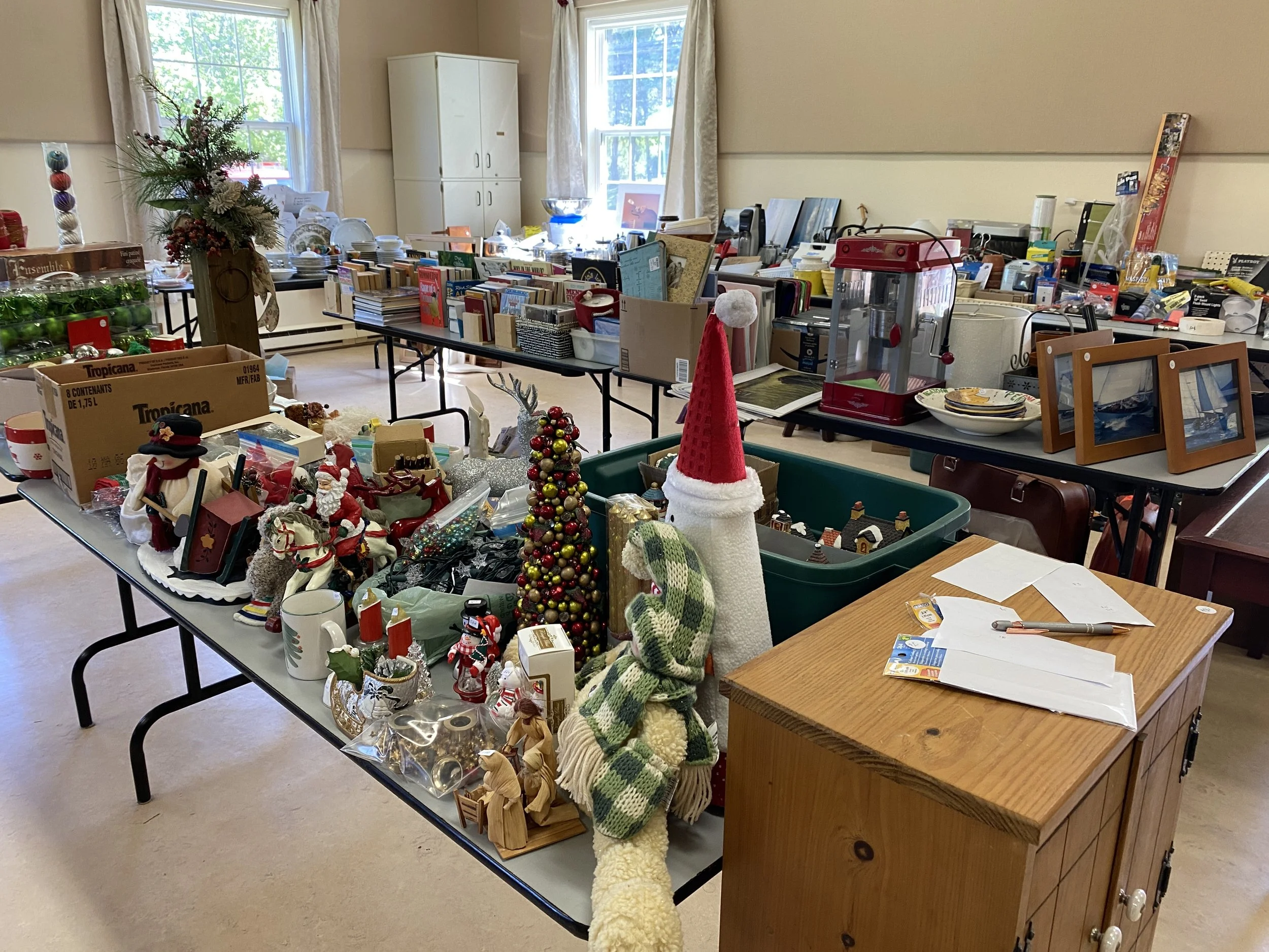 Most years we hold a large and well attended yard sale. This photo shows tables piled high with donated treasure!