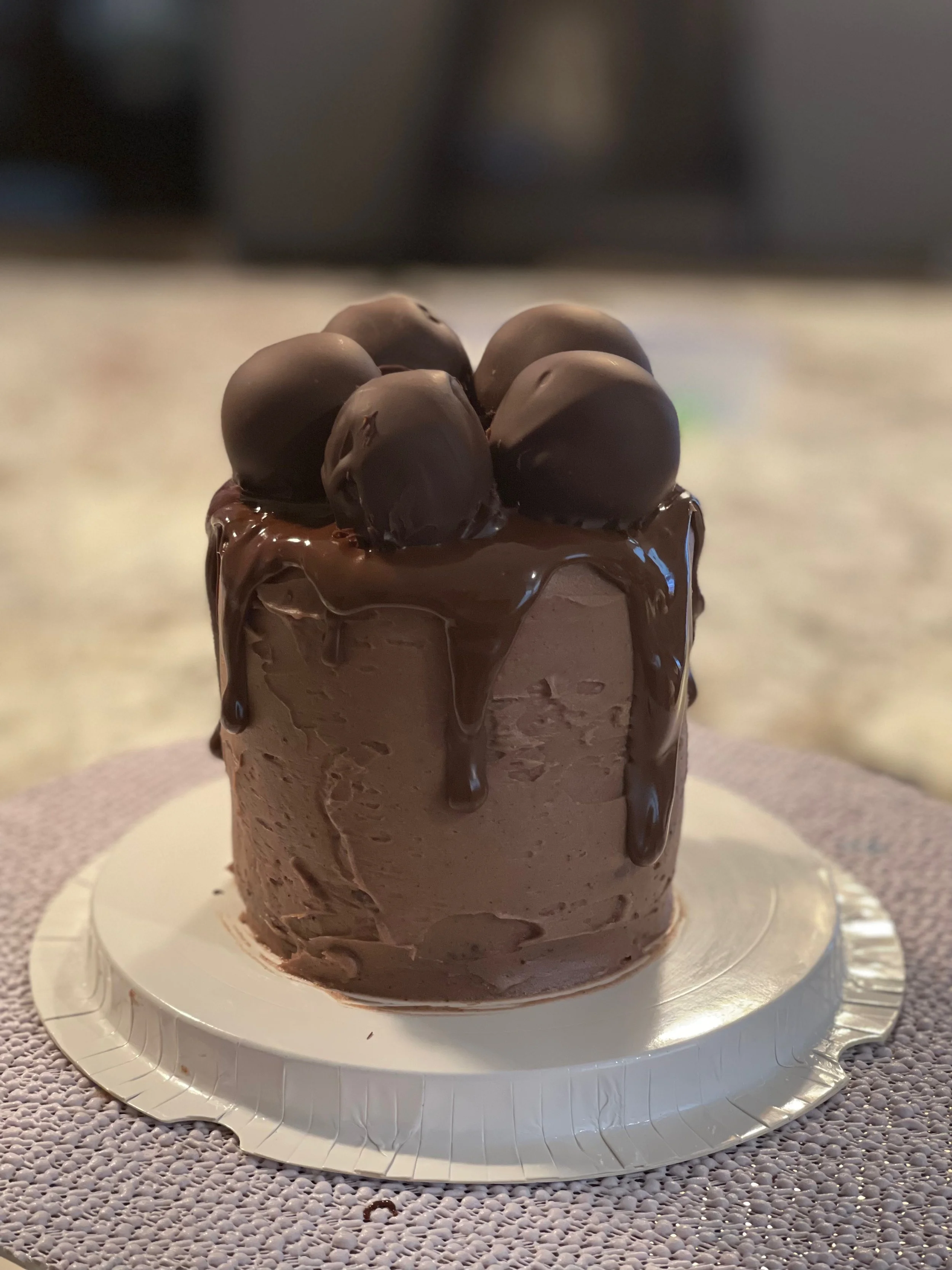 Chocolate cake with chocolate ganache and chocolate truffles on top.