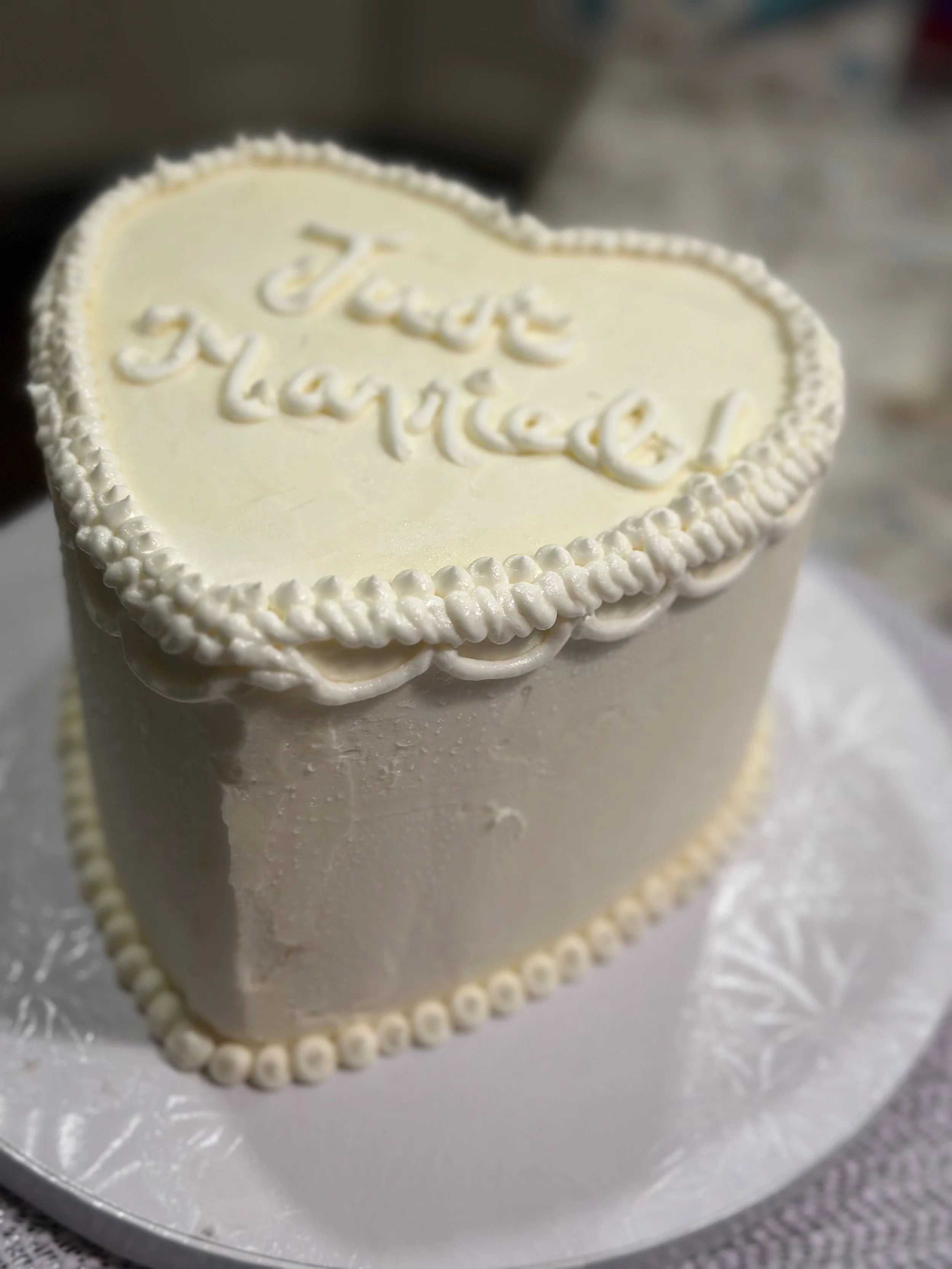 A white cake with a decorative border and the words "Just Married" written on top in white icing.