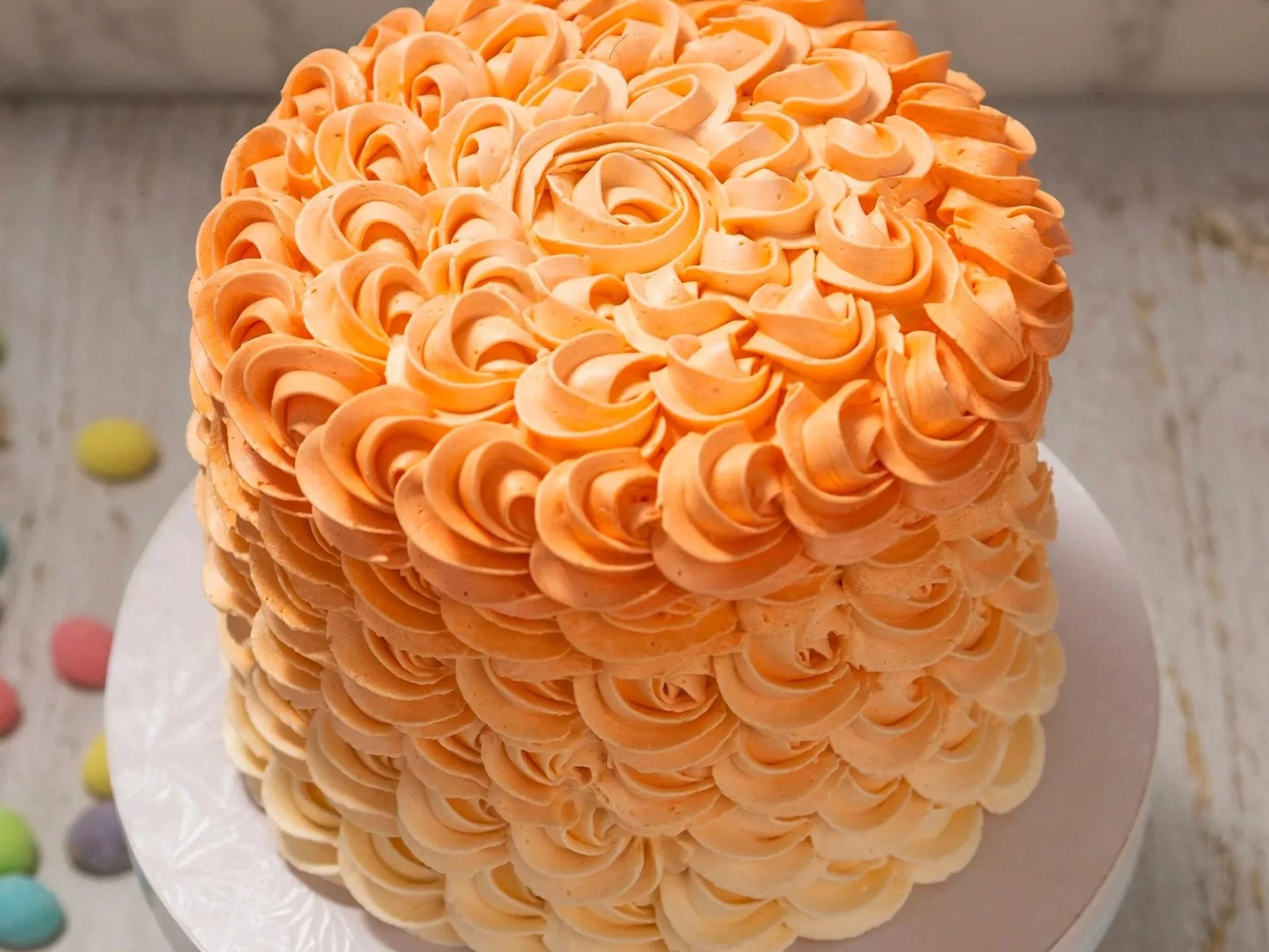 A round cake decorated with peach-colored piped rosettes.