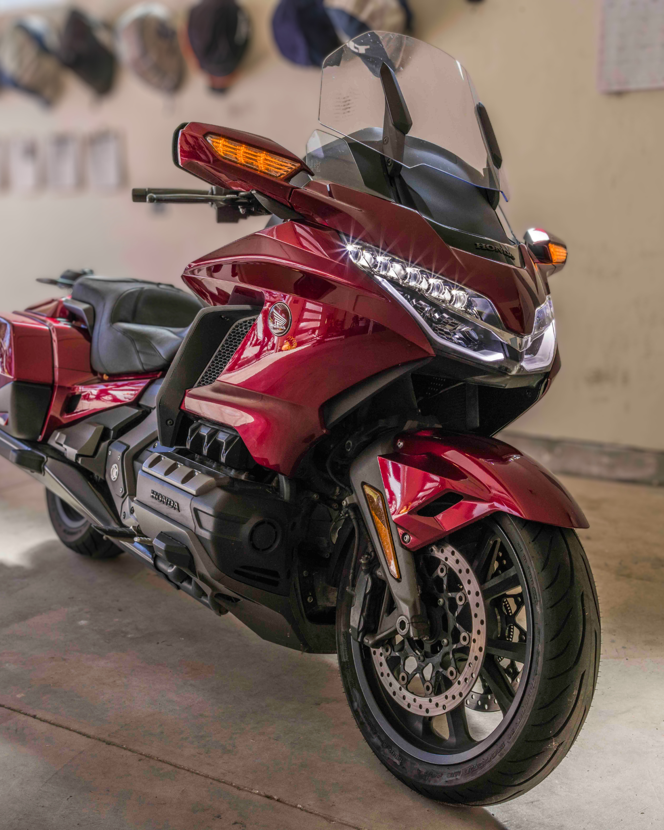 Red Honda touring motorcycle with windshield, front disc brakes, and a black seat parked indoors.