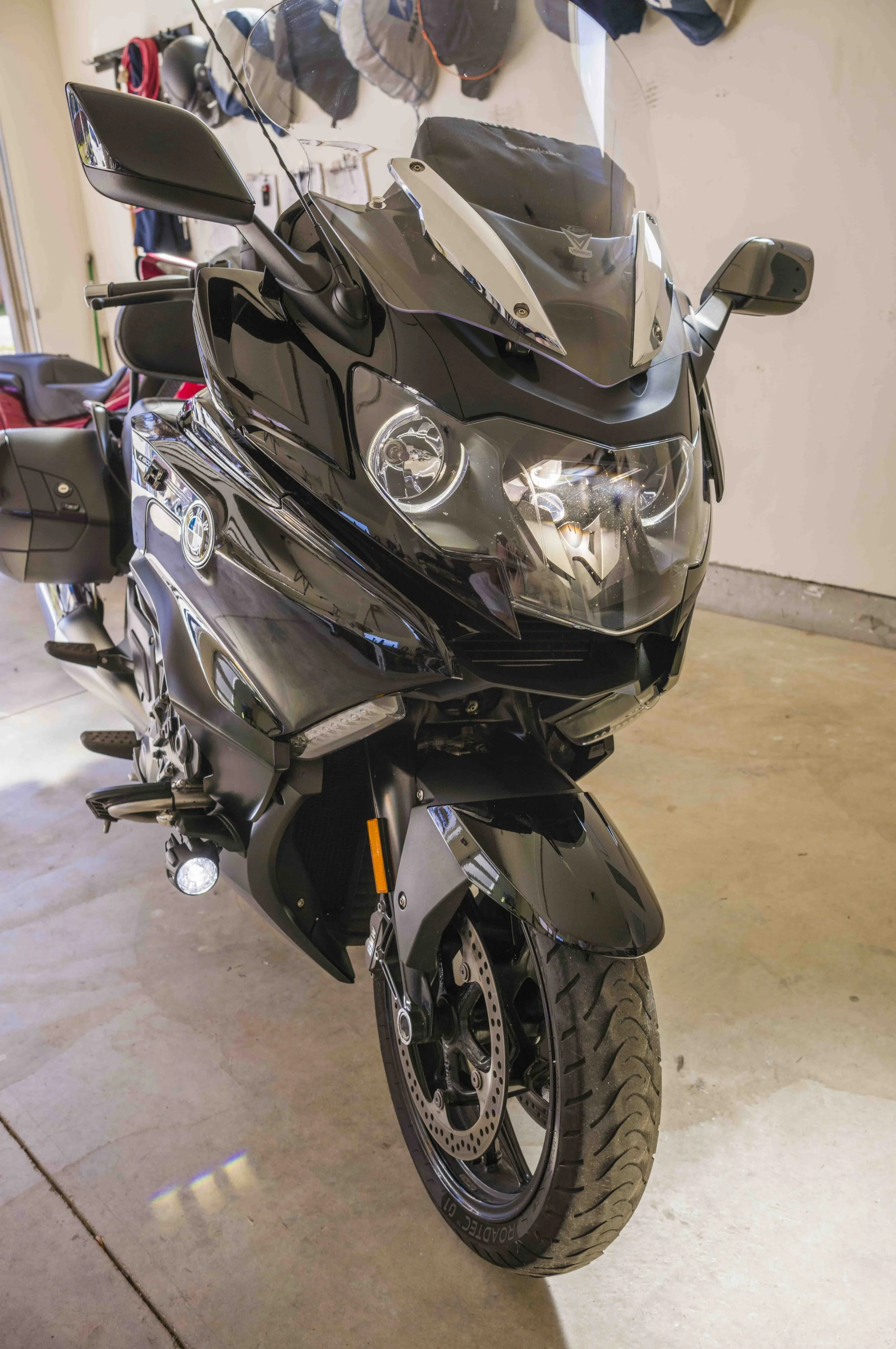 A black touring motorcycle with a windshield, mirrors, and large front tire parked in a garage.
