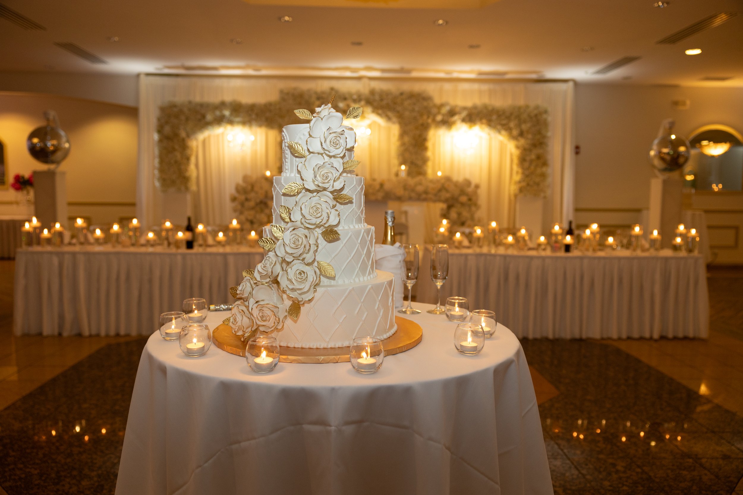 Crystal Palace Banquets decorated with white roses and lit candles for a wedding reception.
