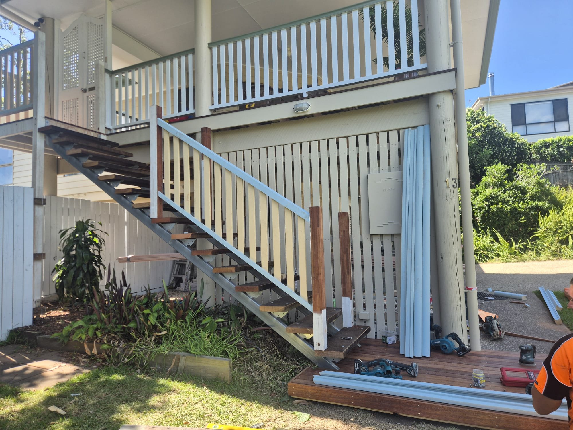 Construction site of an outdoor staircase on a house with tools and materials, with workers installing new materials.