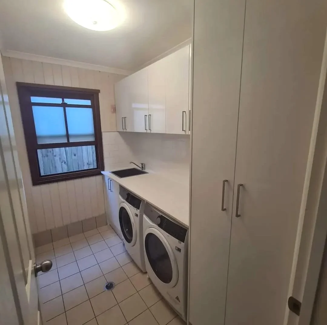 Small laundry room with a window, white cabinetry, a sink, a washer and dryer, and tile flooring.