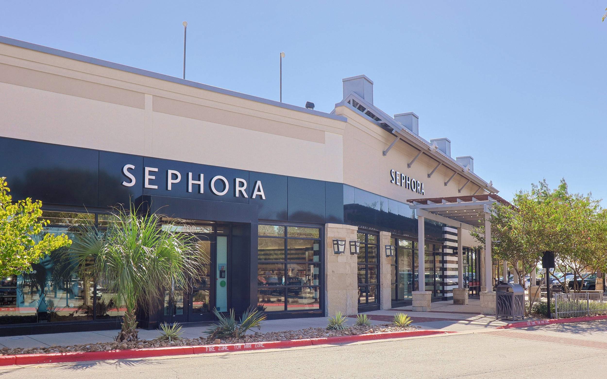 Exterior view of a Sephora store at Wolf Ranch Town Center in Georgetown, TX, with trees, outdoor seating, and a clear blue sky.