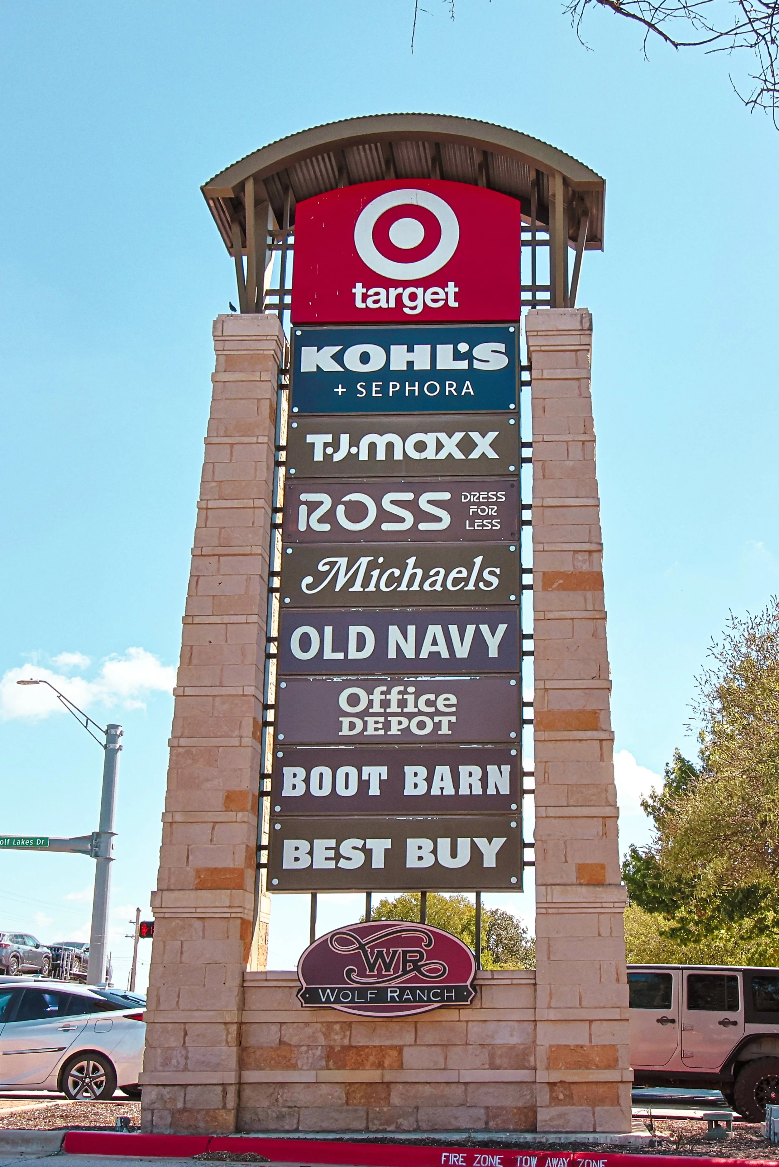 Tall outdoor sign with multiple store names at Wolf Ranch Town Center in Georgetown, TX, including Target, Kohl's, Sephora, T.J. Maxx, Ross Dress for Less, Michaels, Old Navy, Office Depot, Boot Barn, and Best Buy. 