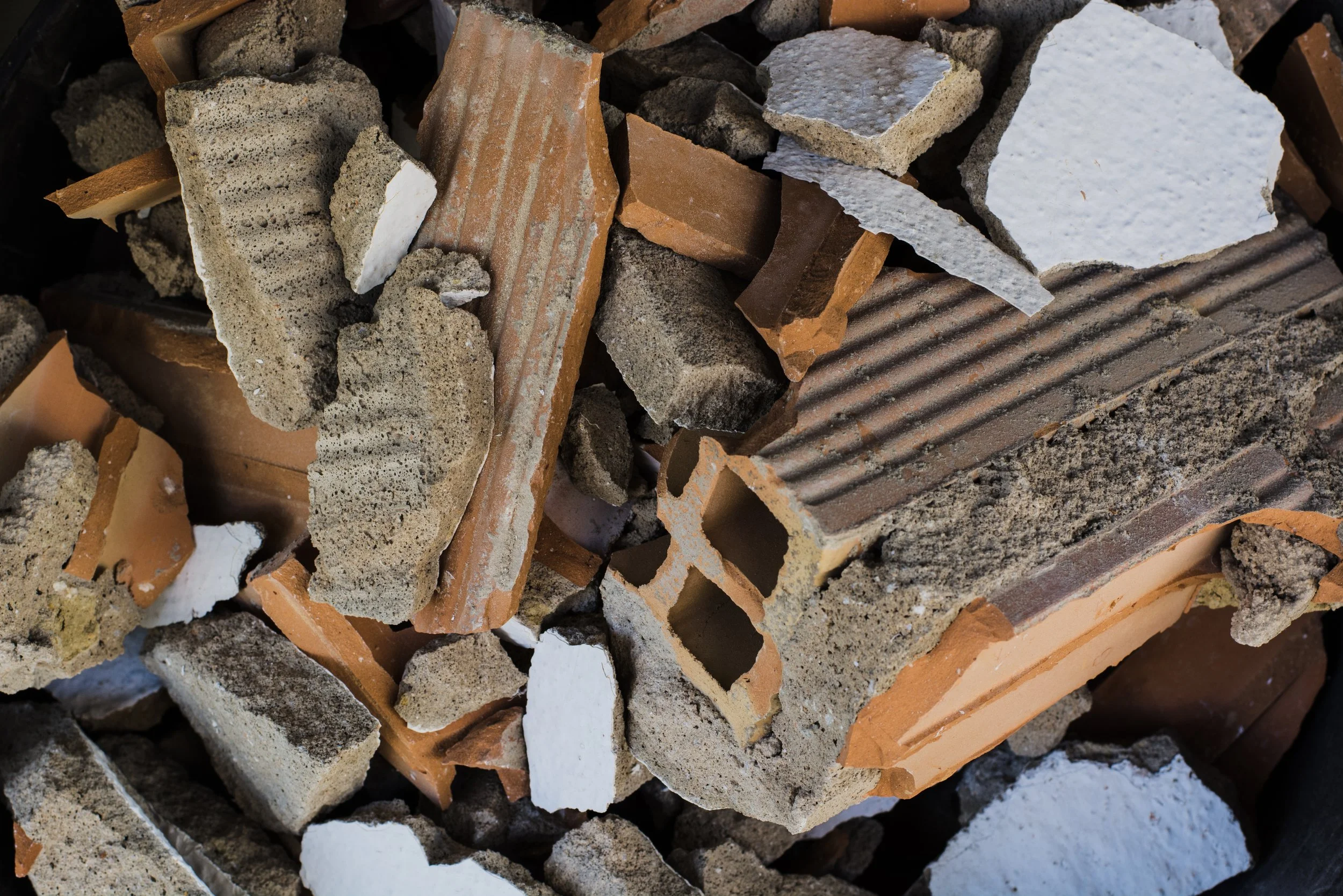 A pile of assorted broken bricks and concrete pieces in various shades of brown, gray, and white.
