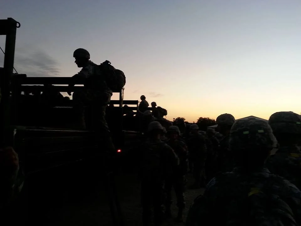 Picture of silhouetted soldiers climbing into military vehicles against a morning sky. Photograph by M. Villafrade - 2013