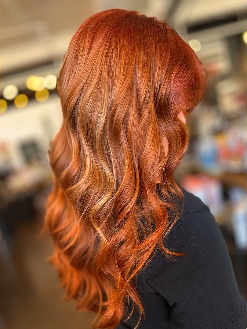 Side view of a woman with long, wavy red hair.