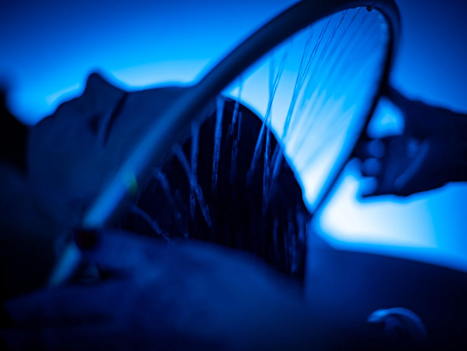 Close-up of client in Japanese Head Spa, illuminated by blue light, with part of the tire and frame visible.