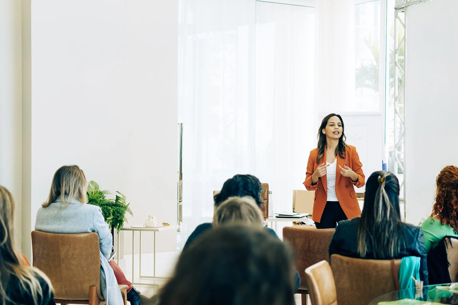 Female speaker addressing a seated audience during a presentation.