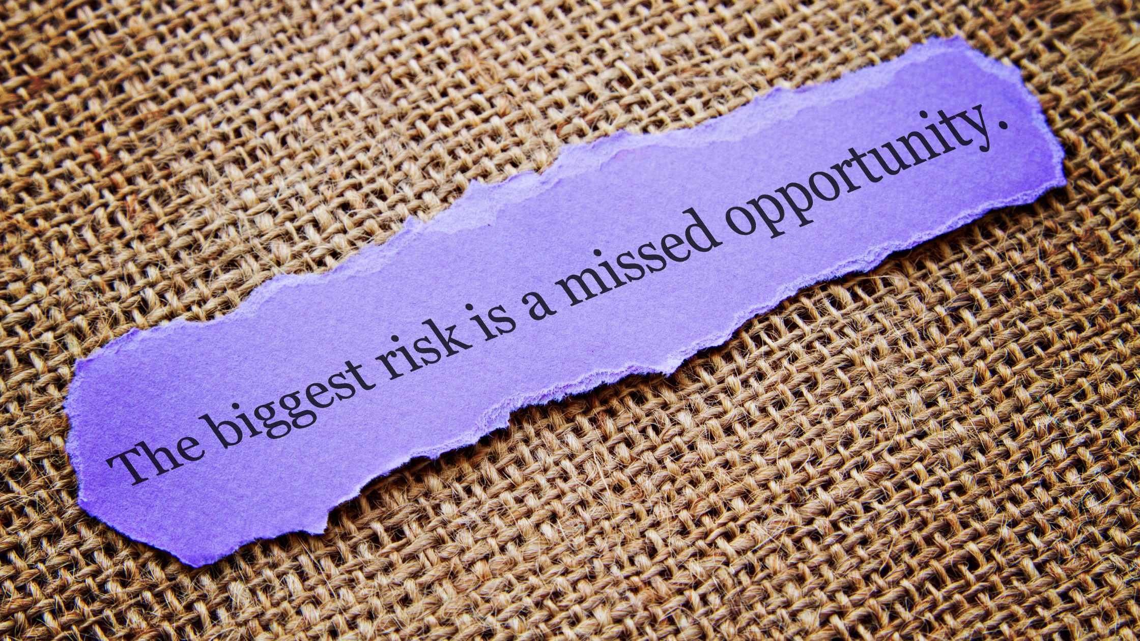 A ripped purple piece of paper reads 'The biggest risk is a missed opportunity'