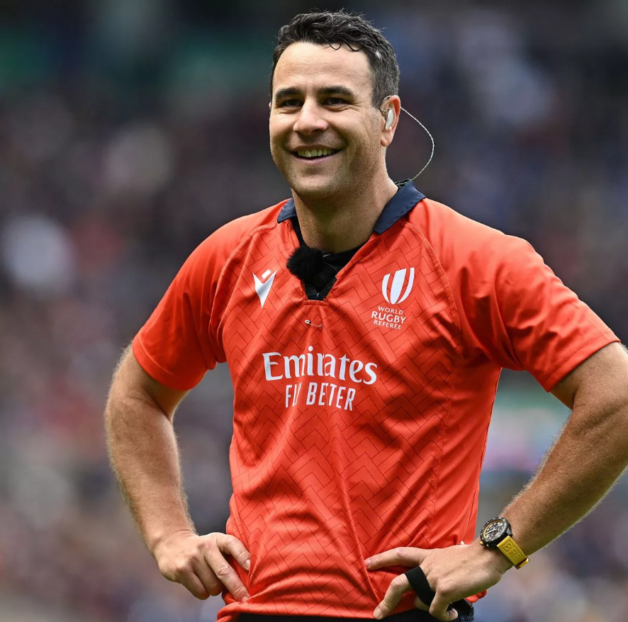 Rugby referee Ben O'Keeffe with his hands on his hips, smiling