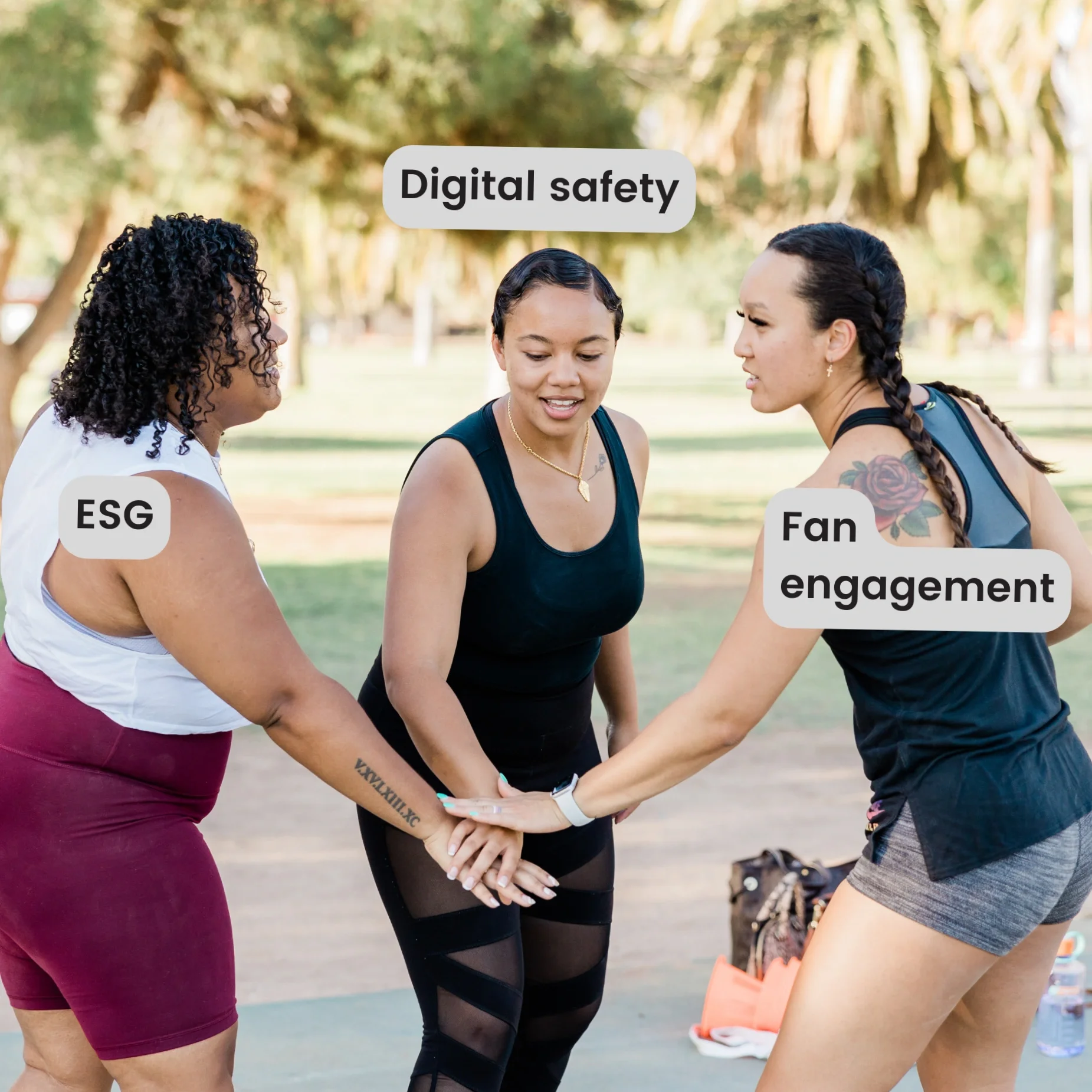 Three women in athletic outfits put their hands in the middle