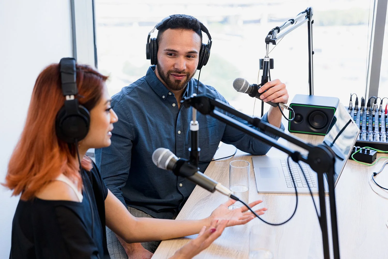Male and female hosts recording a podcast together.