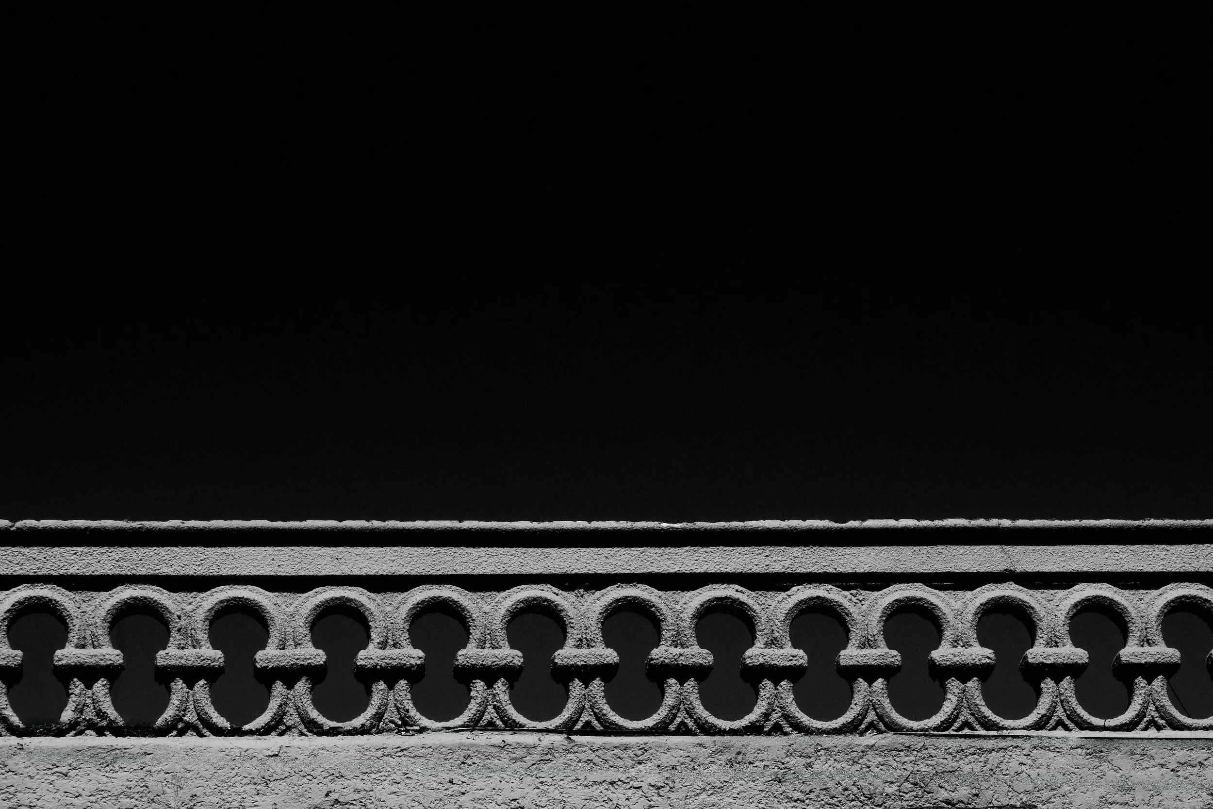 Black background with a white decorative balustrade at the bottom.