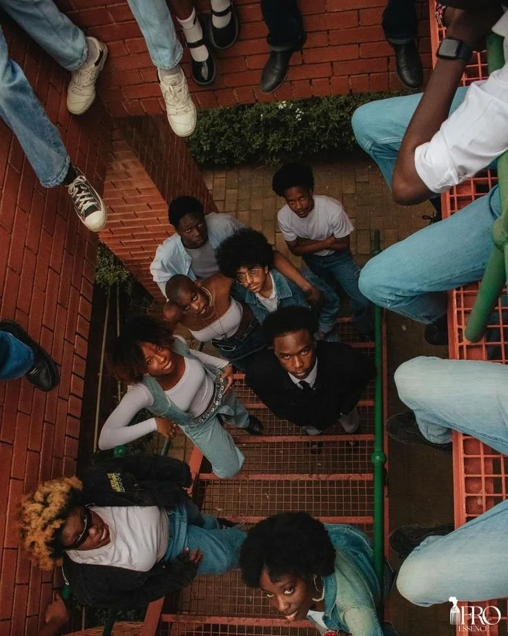 Group of young people standing and sitting around a brick staircase, looking up at the camera.