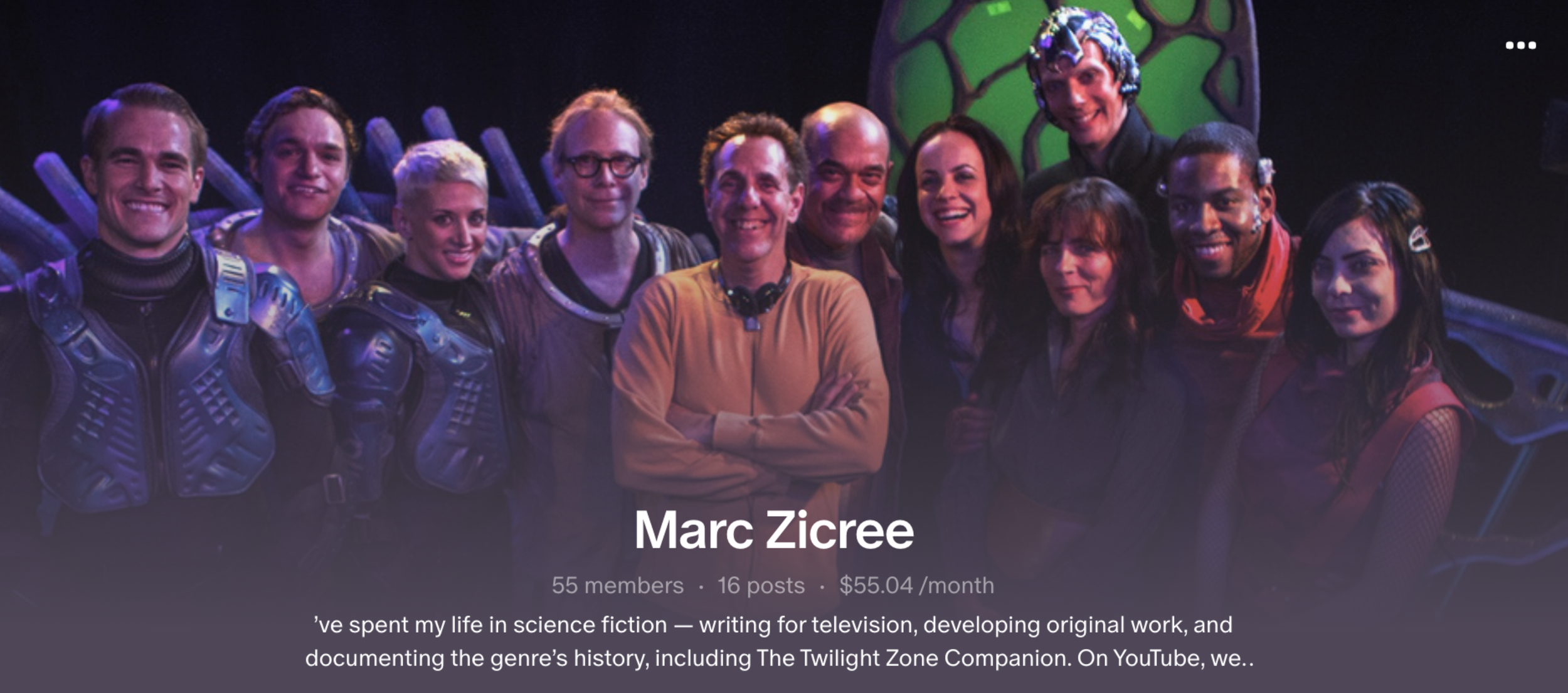 Group of people in science fiction costumes, smiling for a photo, with a green alien-like prop in the background.