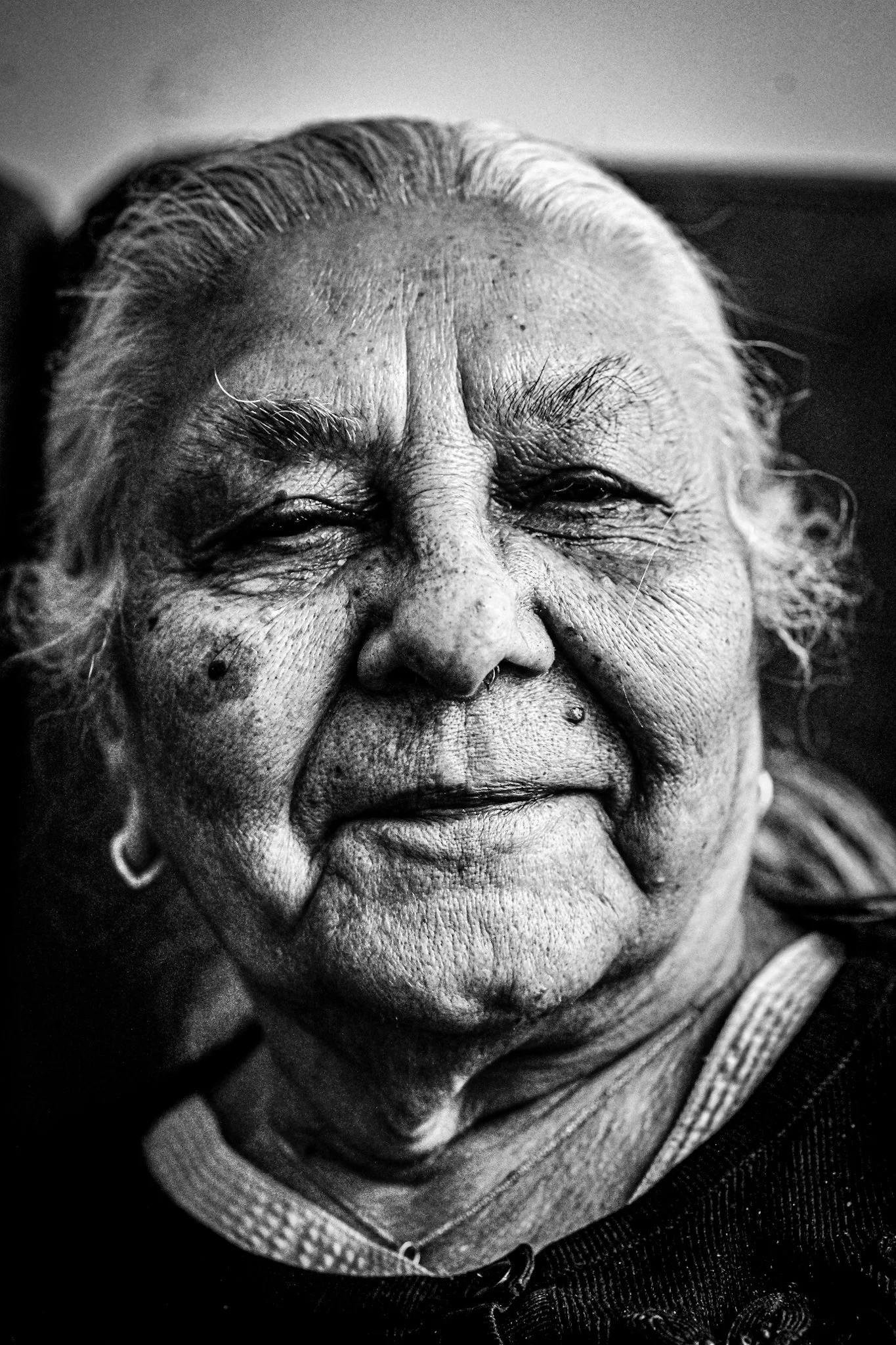 Close-up black and white portrait of an elderly woman with gray hair, smiling gently.
