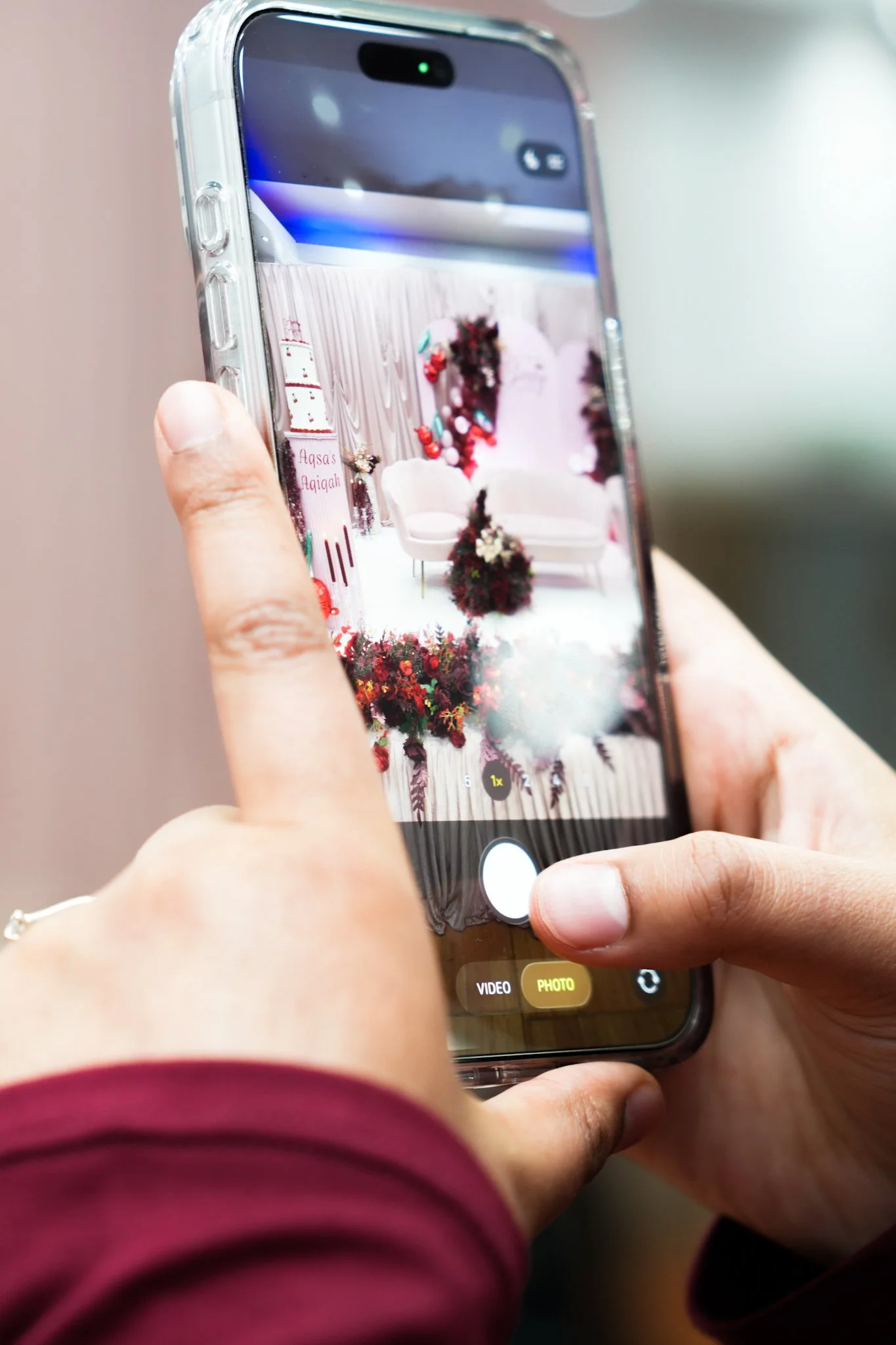 Person taking a photo of a decorated wedding or event backdrop with a smartphone.
