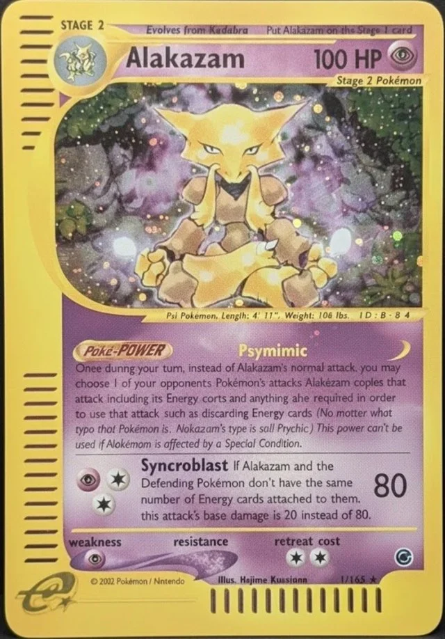 A Pokémon card featuring Alakazam, a yellow psychic type Pokémon with 100 HP. The card shows an illustration of Alakazam with two spoons in its hands, set against a cosmic background. The card describes Alakazam's abilities, including the move PsyMimic and Synrocblast, and includes details like its height, weight, and ID number.