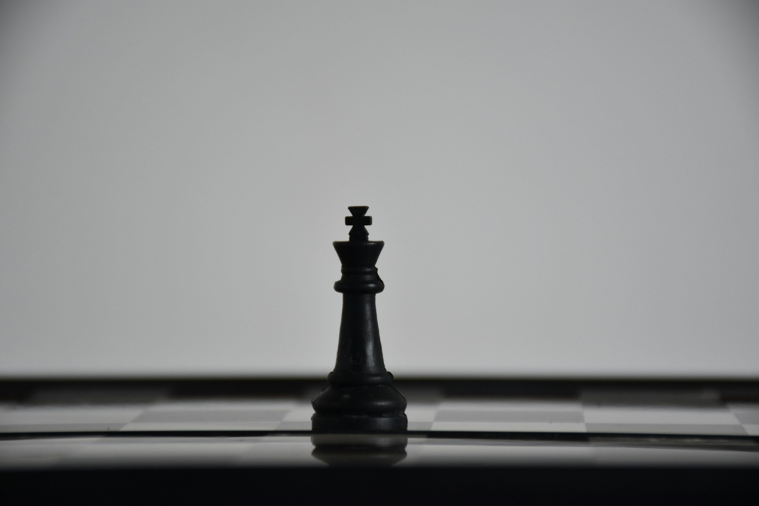 Black-and-white photo of a lone black chess piece on a board, representing high-stakes performance