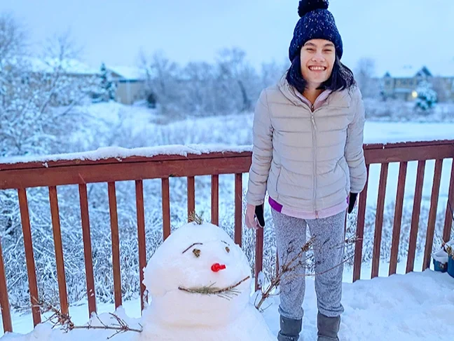 a child with Prader-Willi Syndrome by a snowman