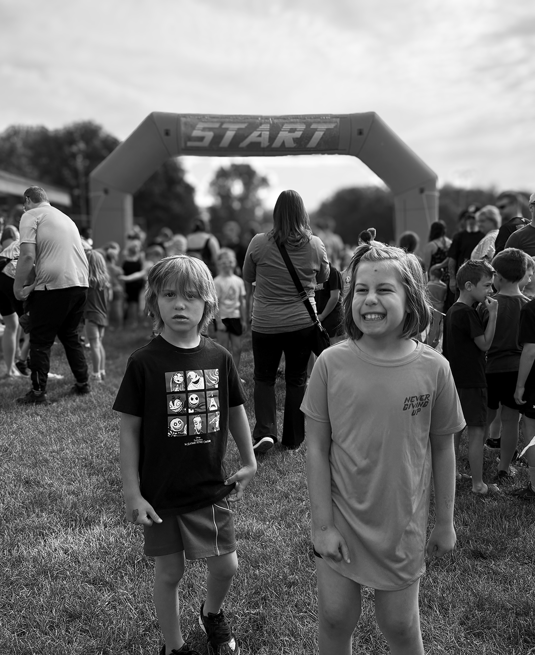 Children at the starting line of a race under an inflatable arch with the word 'START' in the background.