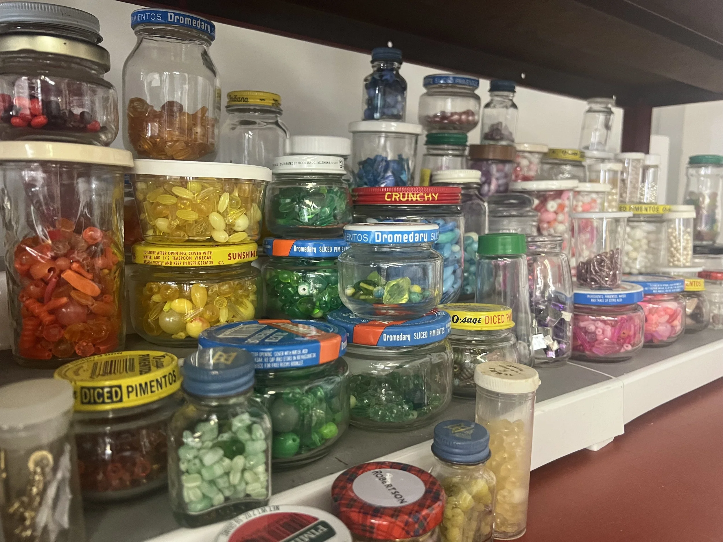Assorted jars containing colorful candies and sweets on a kitchen shelf.