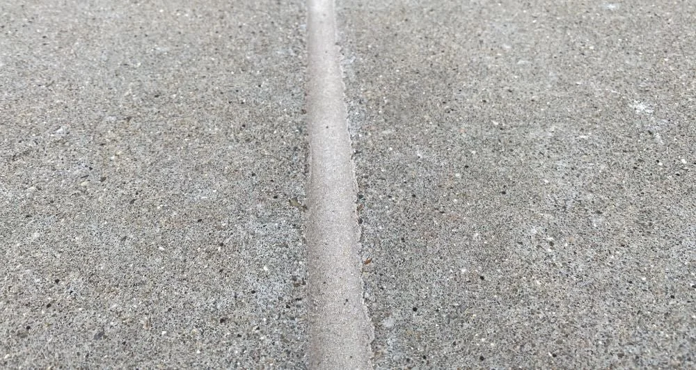 Close-up of a concrete sidewalk with a small crack running through the middle.