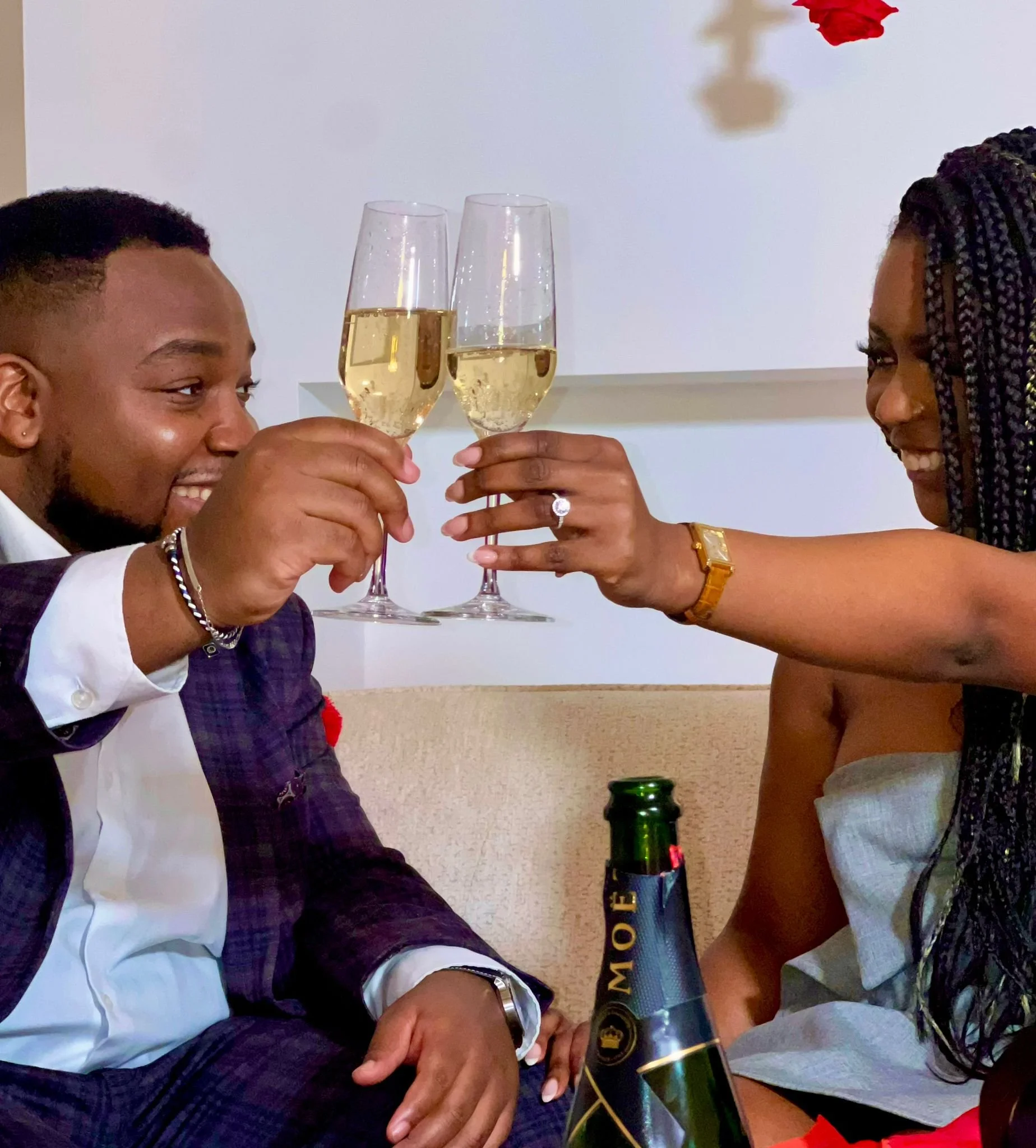 Un homme et une femme portant des vêtements élégants se congratulent en levant deux flûtes de champagne, lors d'une célébration, avec une bouteille de champagne Moët en premier plan.