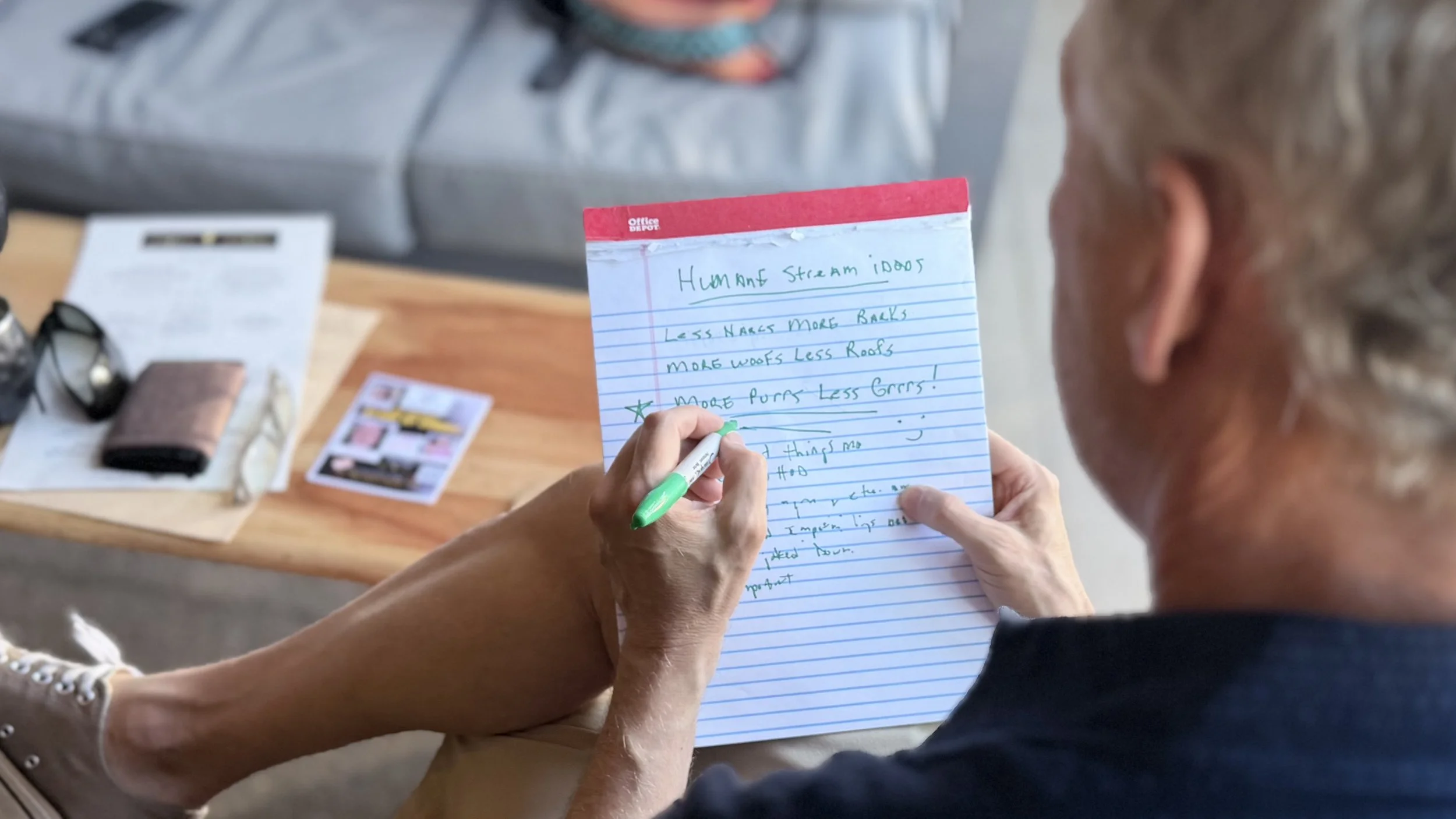 An over-the-shoulder image of a man writing on a note pad
