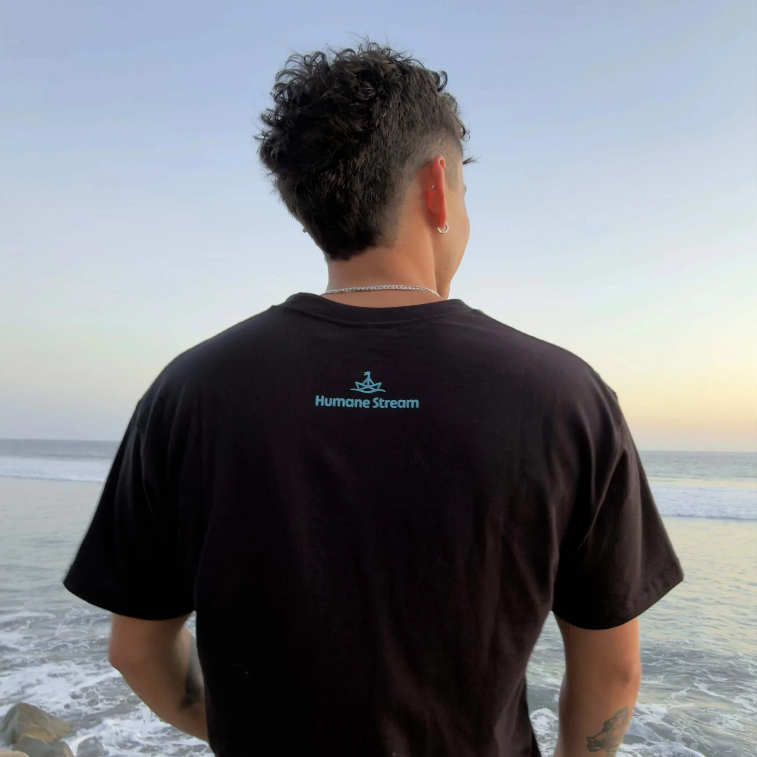 An image of a man from behind wearing a black t-shirt with a Humane Stream logo