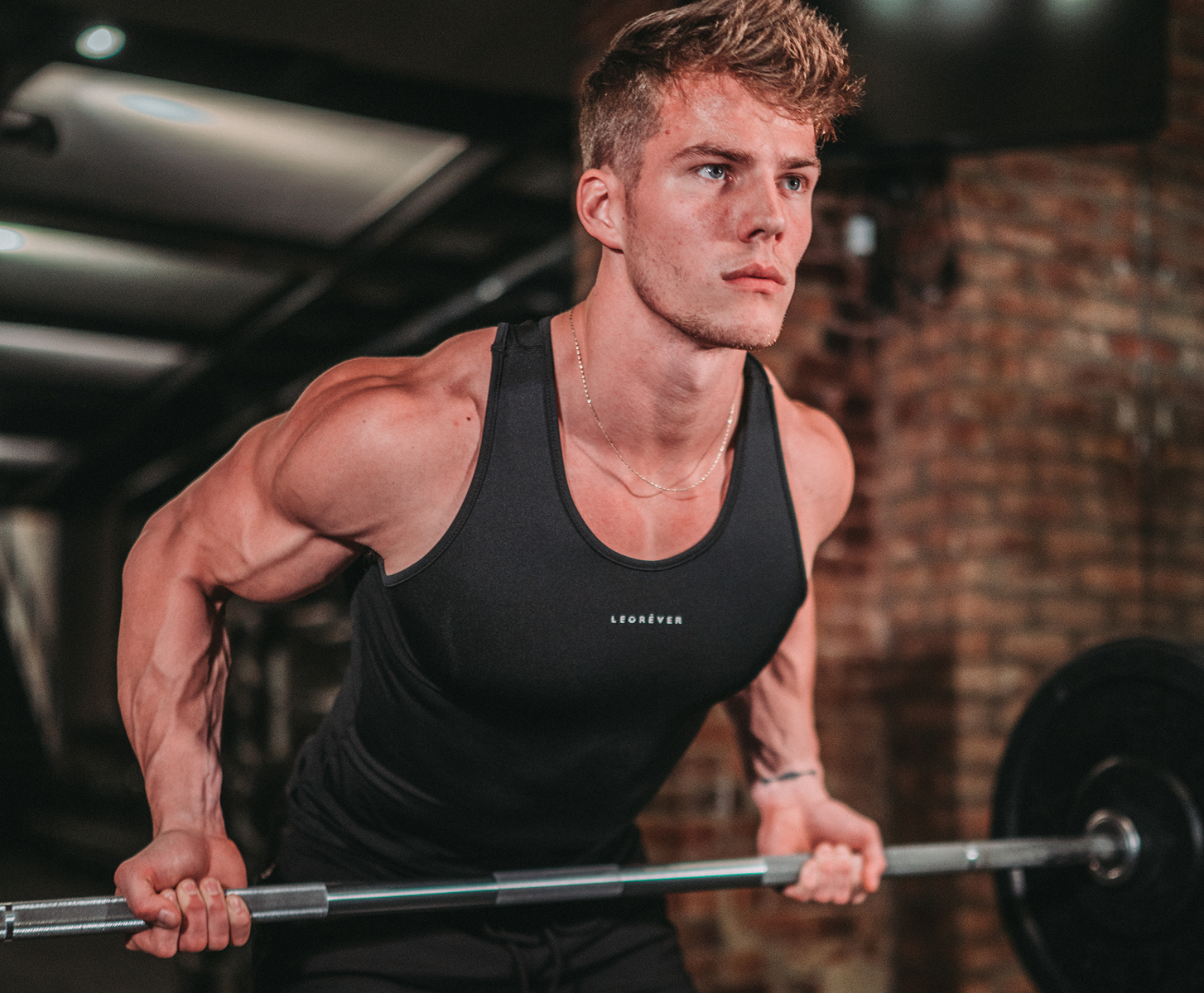 Fitness Coach Michael Dean Johnson training lifting a barbell in a gym with brick walls.