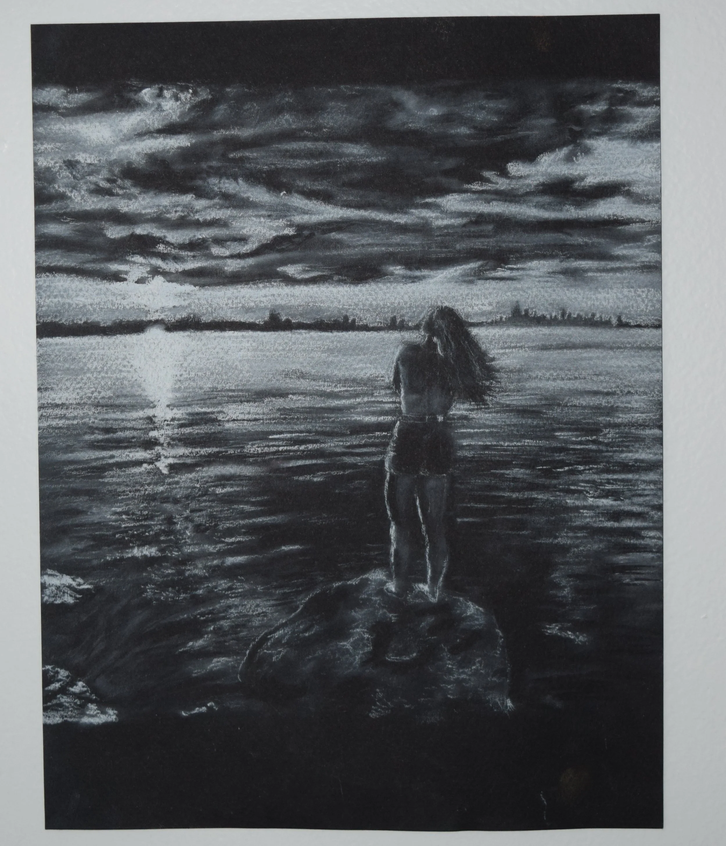 A monochrome drawing of a woman standing on a rock at the edge of a lake, with her back to the viewer, gazing at the sunset and distant city skyline across the water. Clouds fill the sky, reflecting on the water's surface.