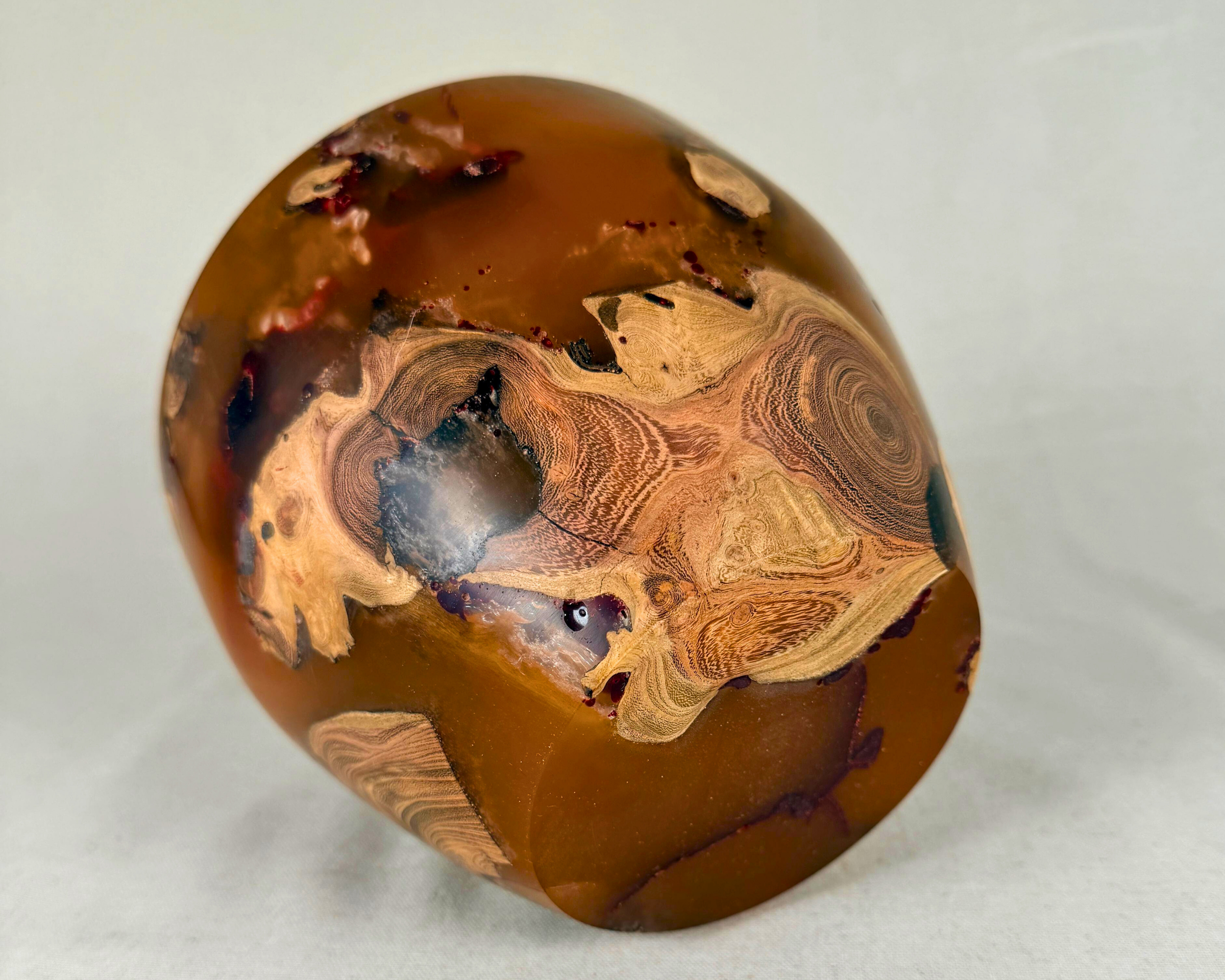 Bottom view of the driftwood and epoxy vessel showing the rounded base, embedded natural wood inclusions, and rich amber-ochre resin composition.