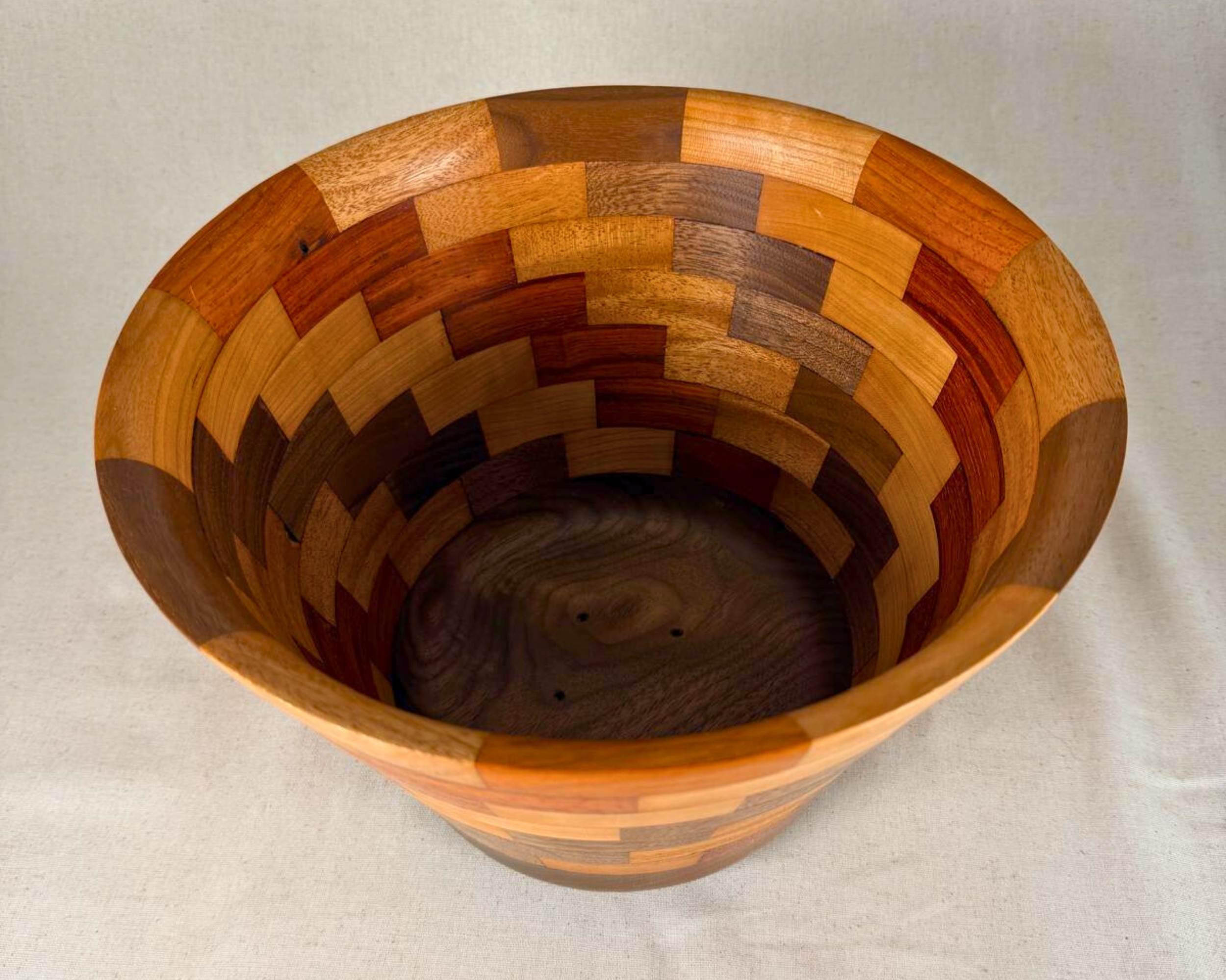 Top view into the segmented vessel, showing the full interior pattern, wide mouth, and contrasting hardwood blocks descending toward the base.