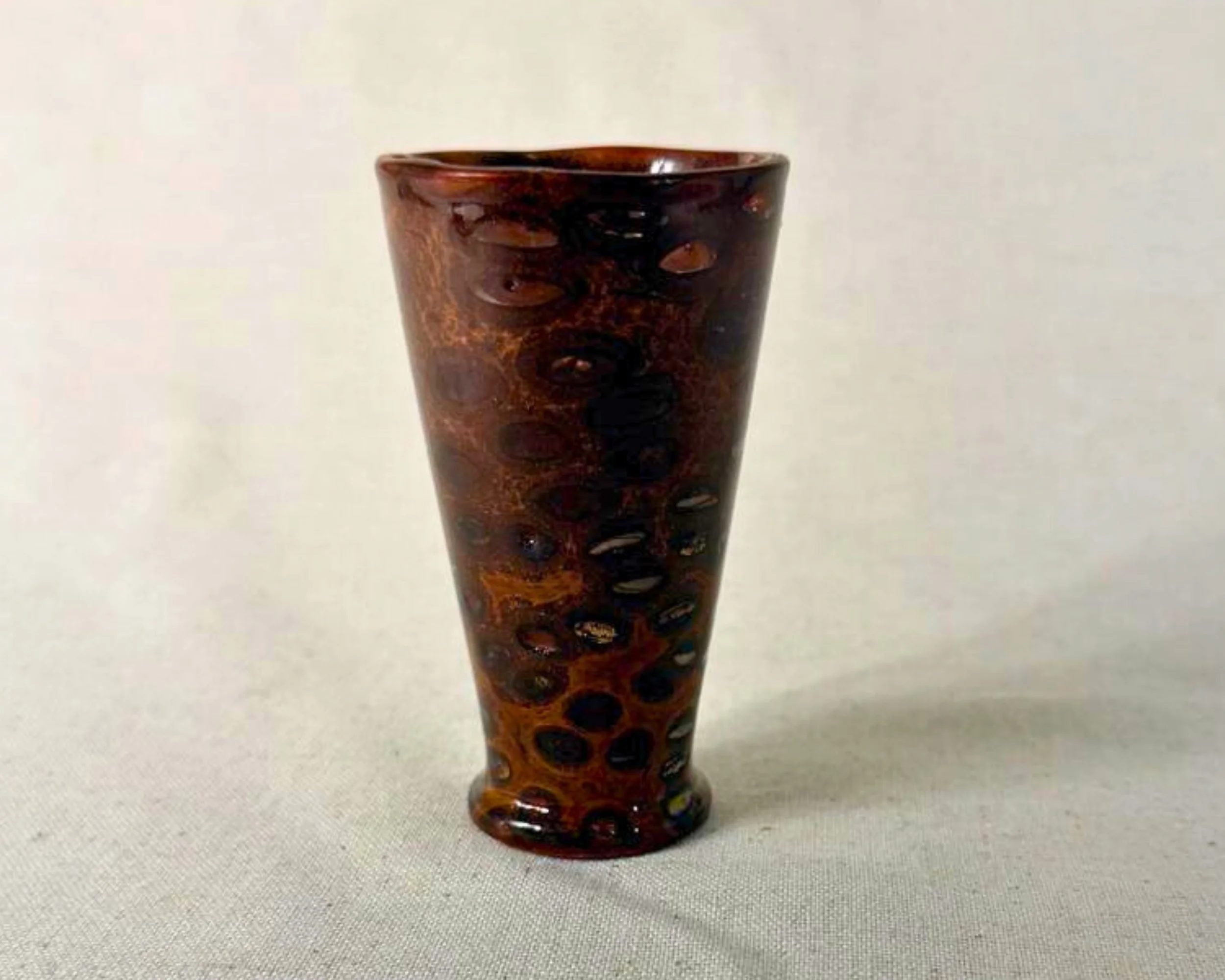 Side profile of a hand-turned banksia nut and red epoxy vessel showing the tapered silhouette and filled natural voids.