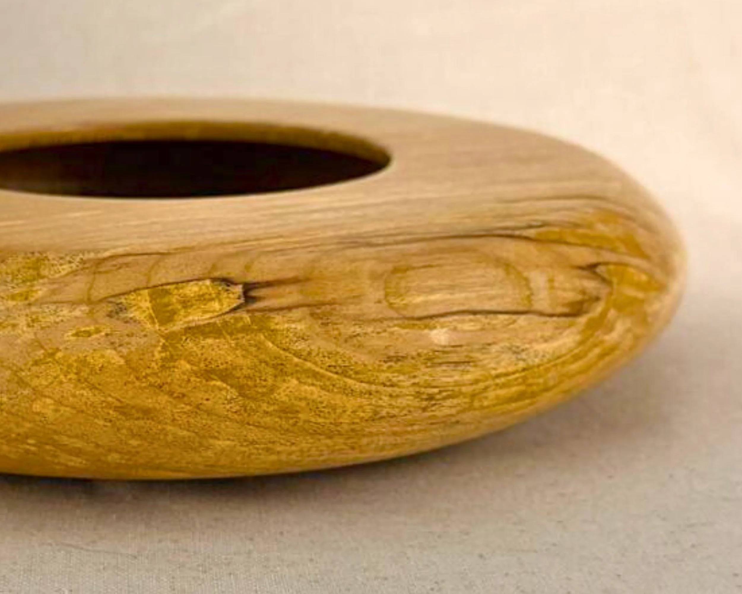 Side profile of a figured maple closed form vessel showing the low height and rounded, flattened form.