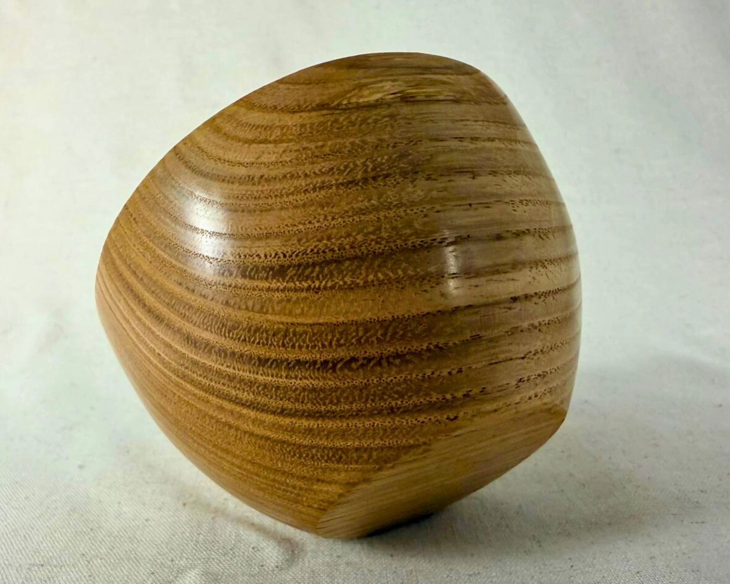 Side-angle view of the oak hollow form showing its rounded profile and sweeping grain bands.